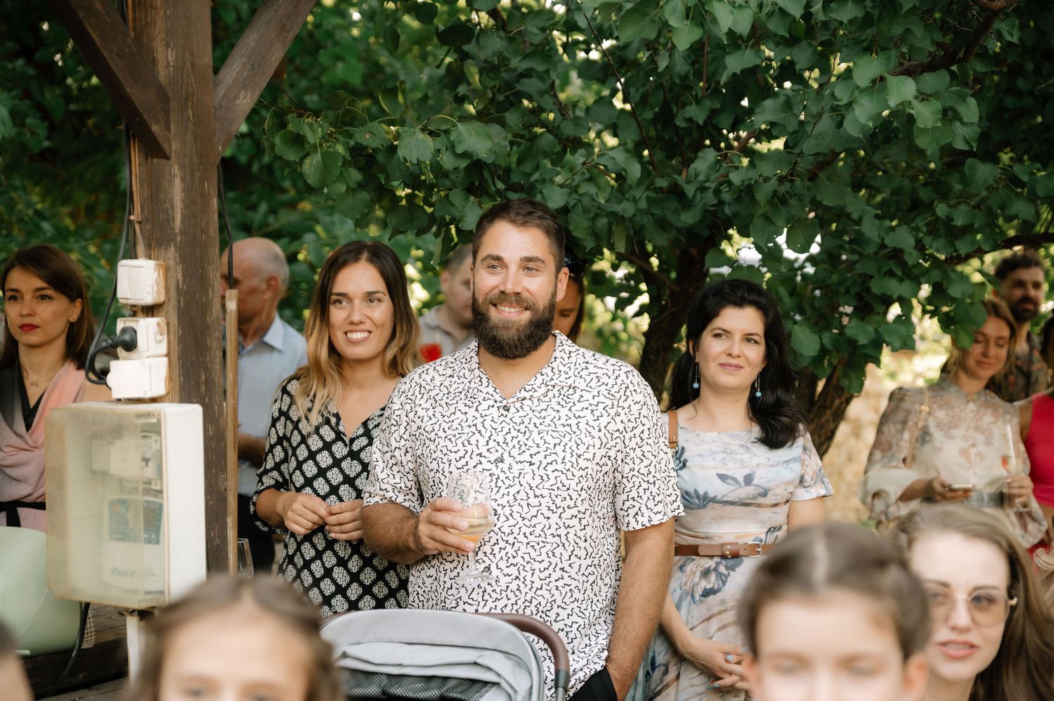 A group of people gather under a wooden pavilion for an outdoor social event.