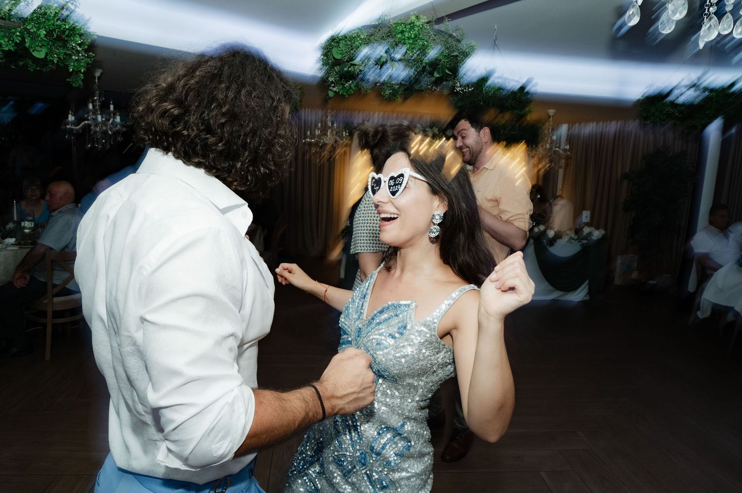 People dancing energetically at a party with festive atmosphere under dark moody lighting.