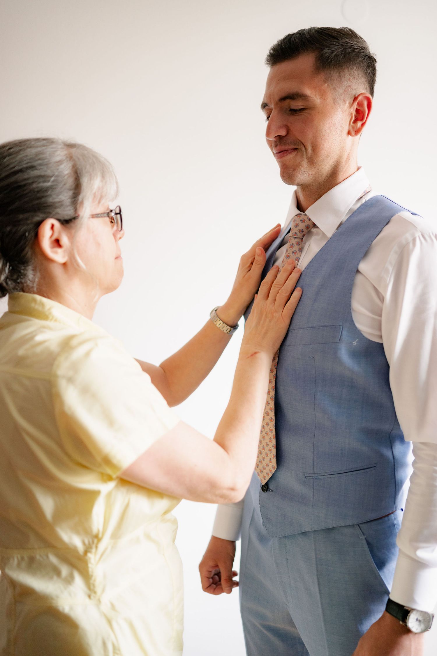 A series of photos showing someone adjusting a tie and vest on a person wearing formal attire.