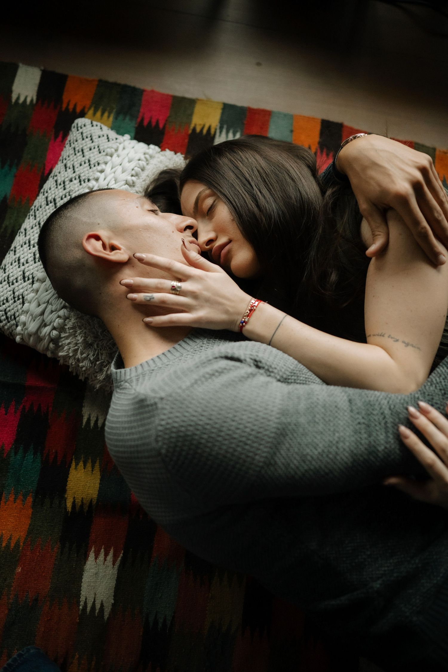 A series of artistic photographs showing someone resting on a colorful patterned couch in dim lighting.