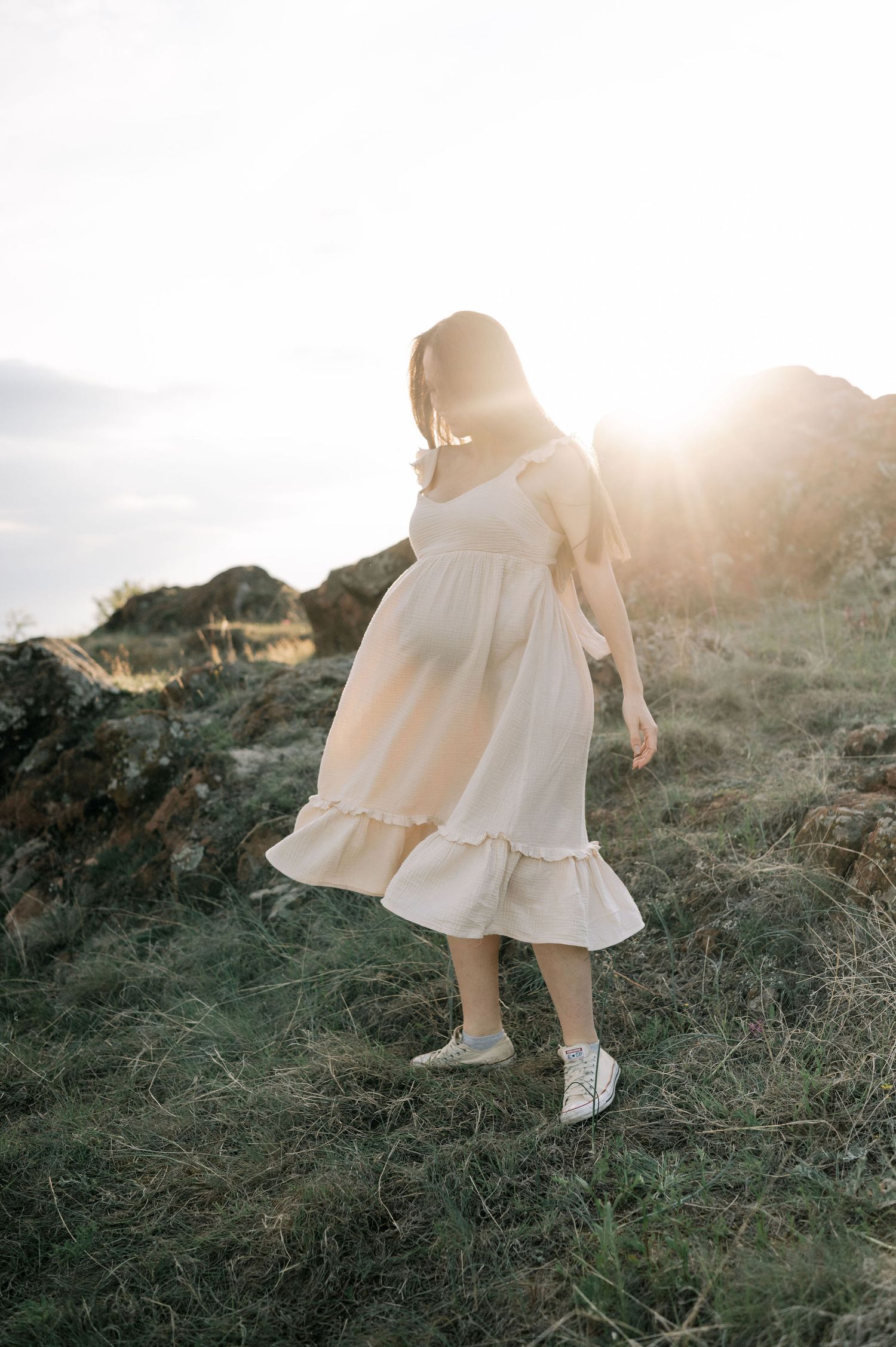 A dreamy sequence shows someone in a flowy white dress walking through sunlit grass at golden hour.