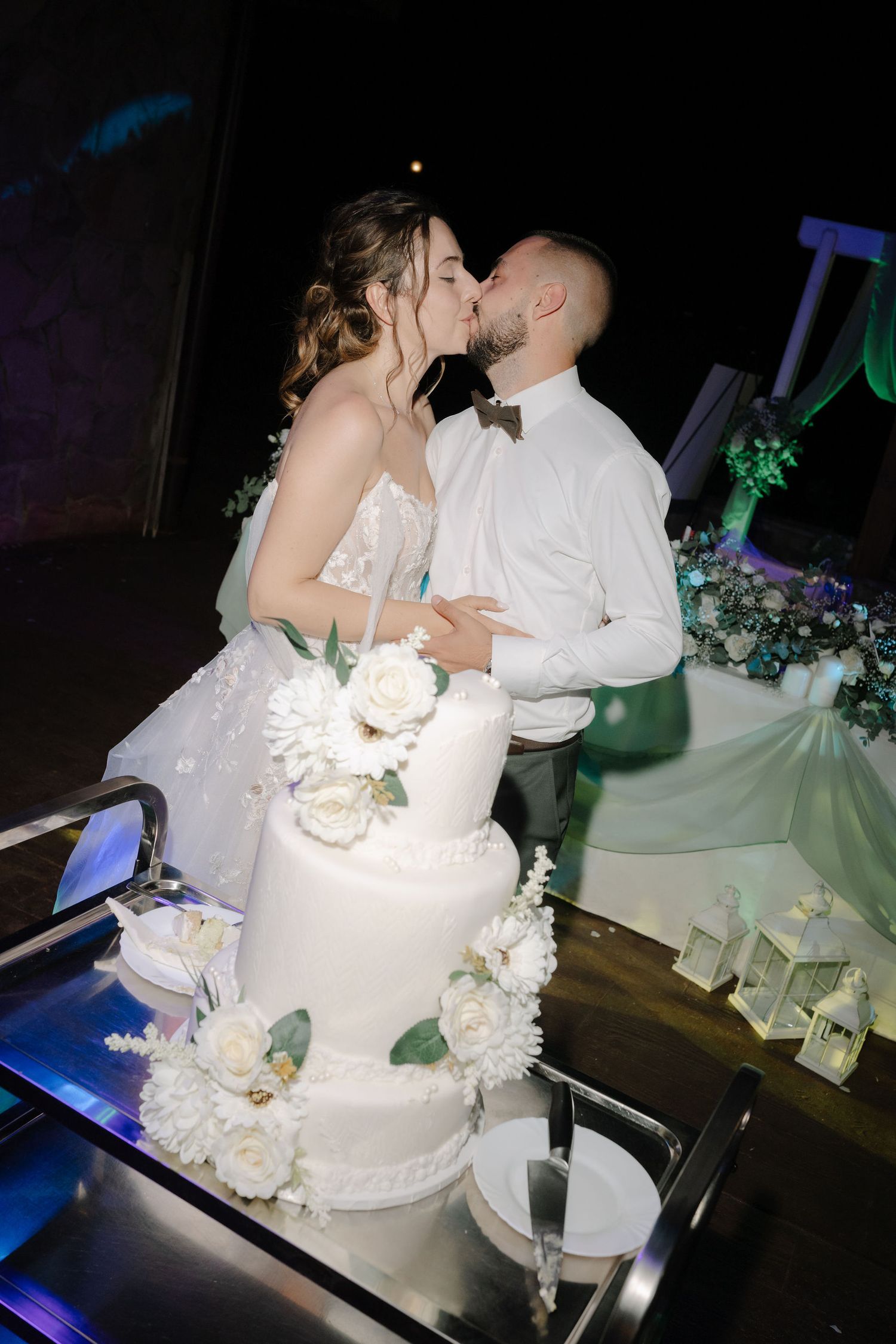 A wedding cake cutting sequence showing a white tiered cake decorated with flowers being sliced by newlyweds at a reception.