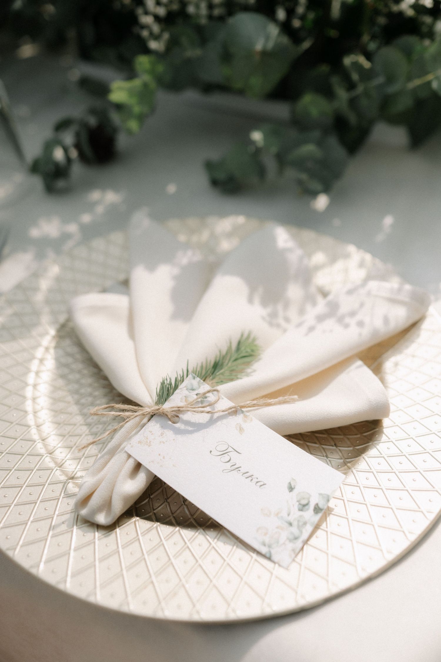 Elegant white place settings with delicate greenery accents arranged on textured plates create a sophisticated table decor.