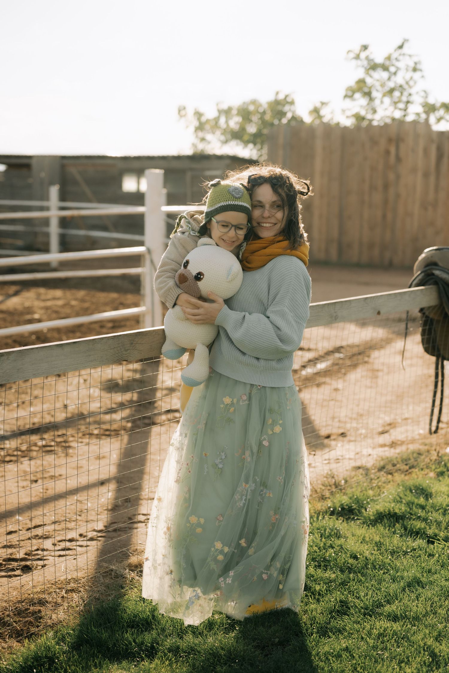 A series of outdoor photos showing two people embracing in a garden setting with wooden fencing at sunset.