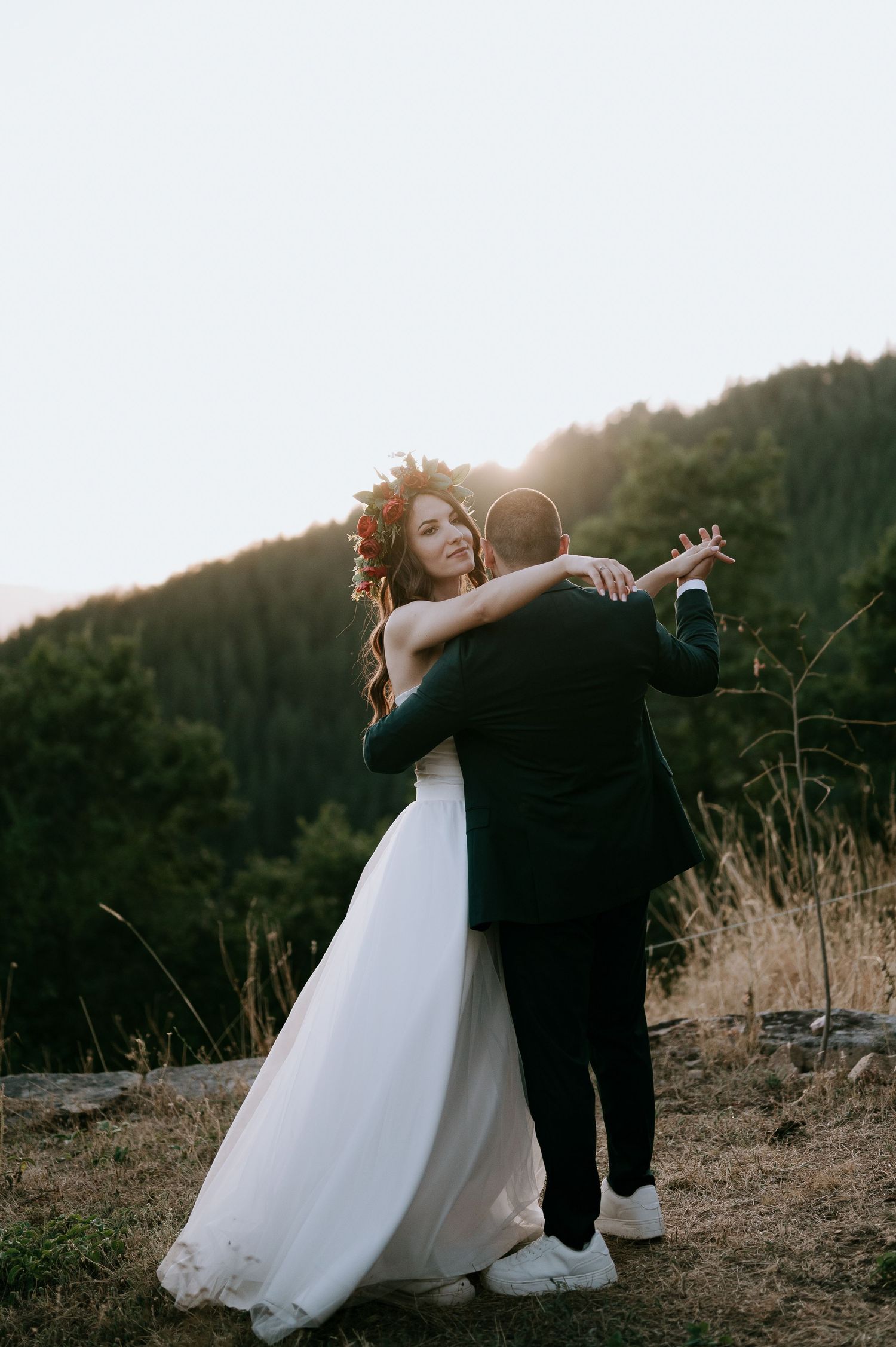 A couple shares an intimate dance moment at sunset in their wedding attire.