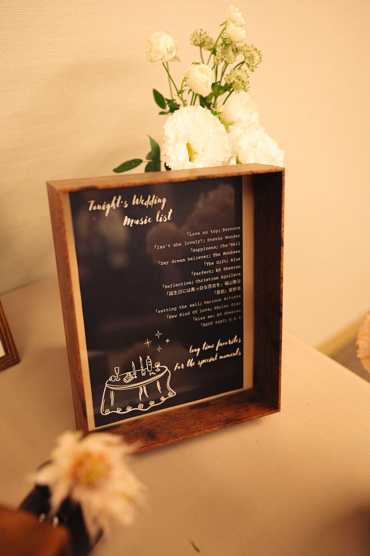 Rustic wooden frames displaying wedding program details with white floral accents.