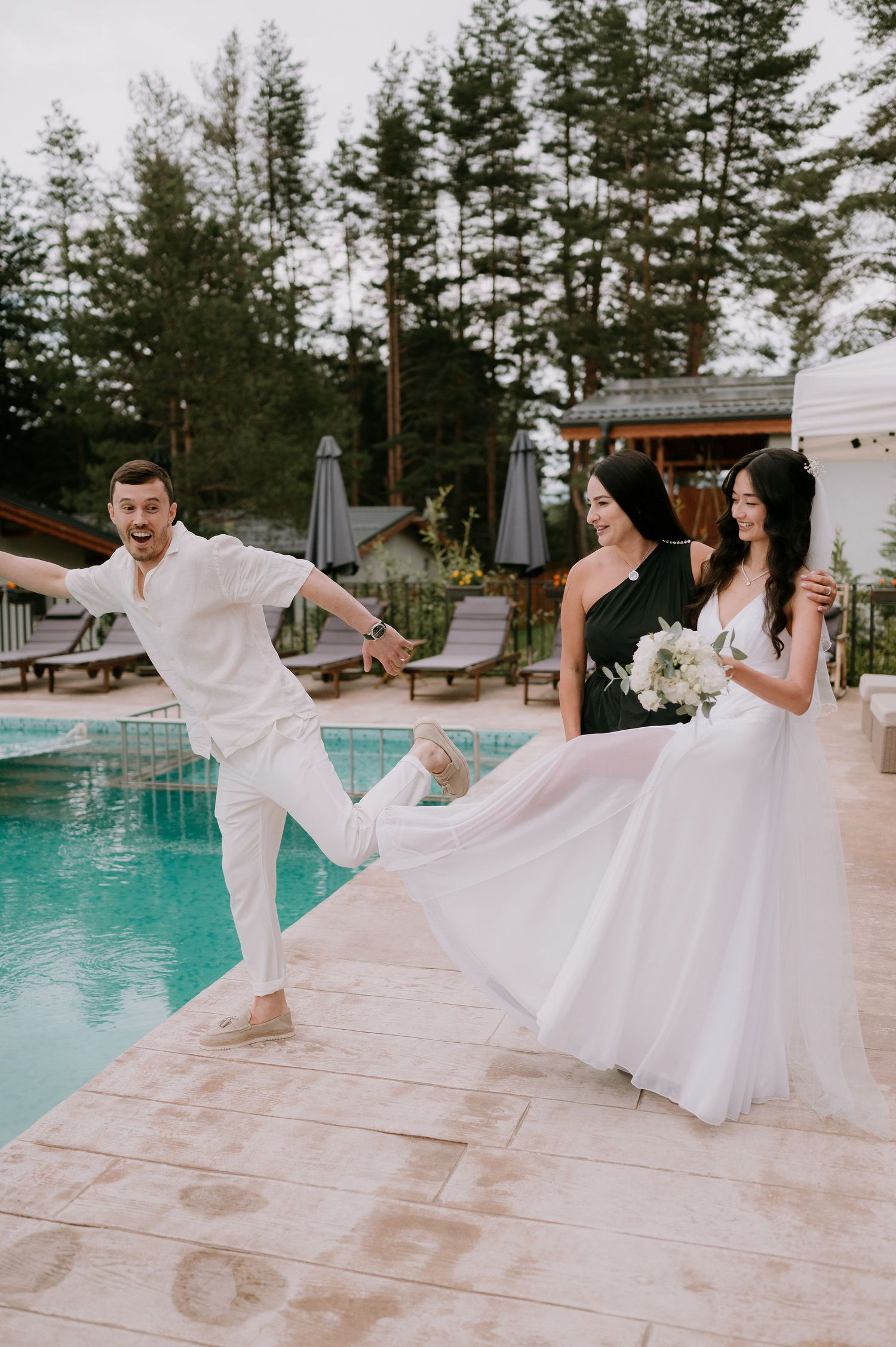 Joyful dancing and celebration moments on a pool deck during a wedding.