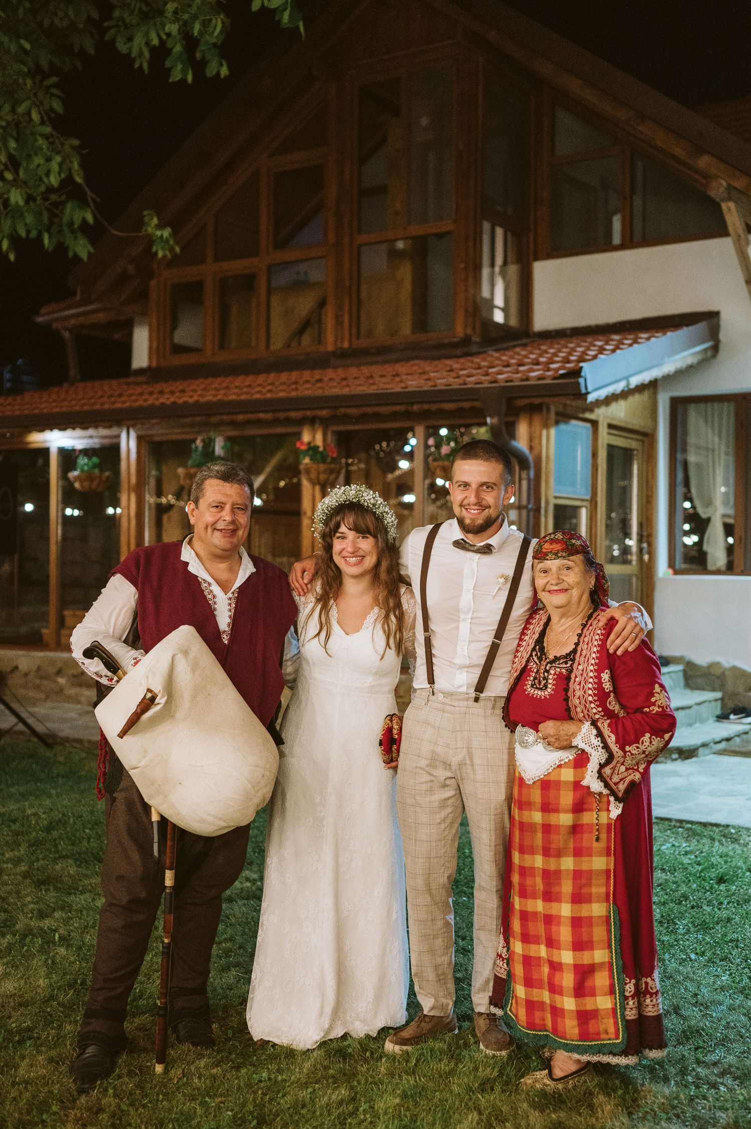 Wedding party members posing together in folk and formal attire at outdoor venue.