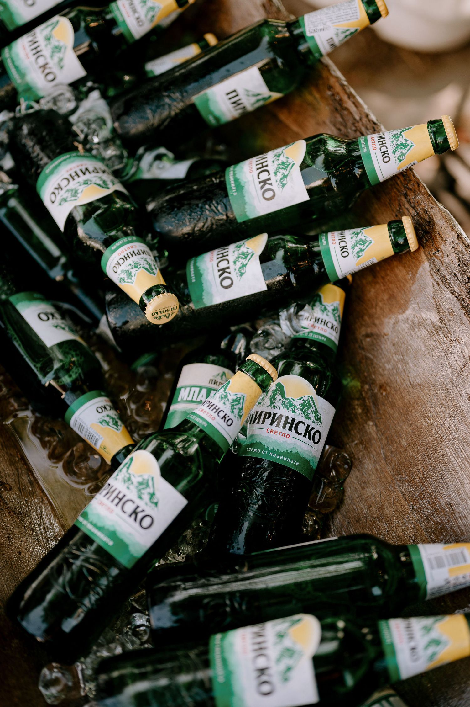 Close-up of used green glass bottles with labels scattered on dark surface.