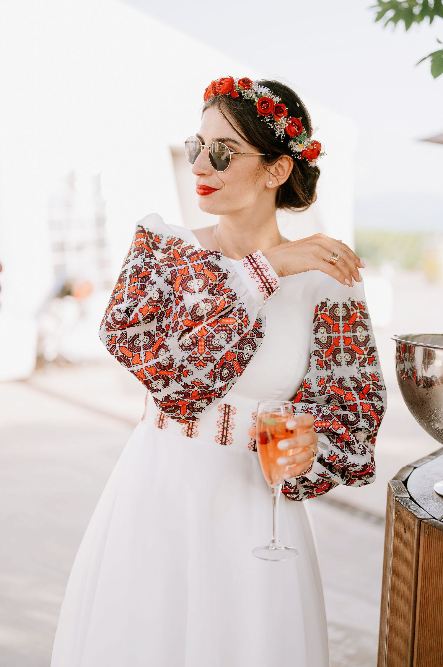 A white dress with red floral puff sleeves is shown in detail shots at an outdoor venue.