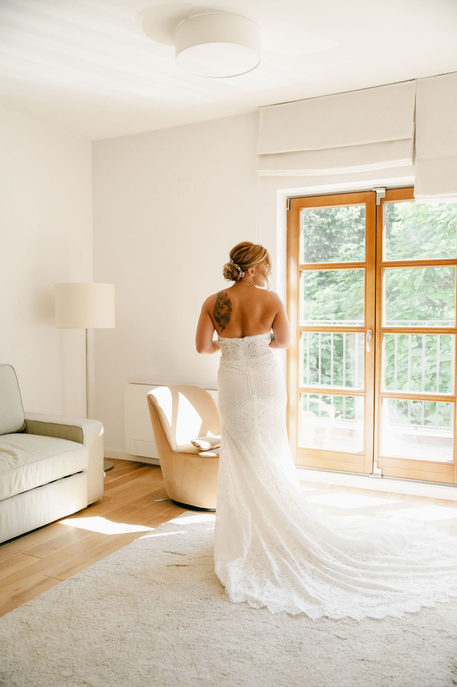 Sunlight streams through wooden windows onto a flowing white wedding gown in a minimalist room.