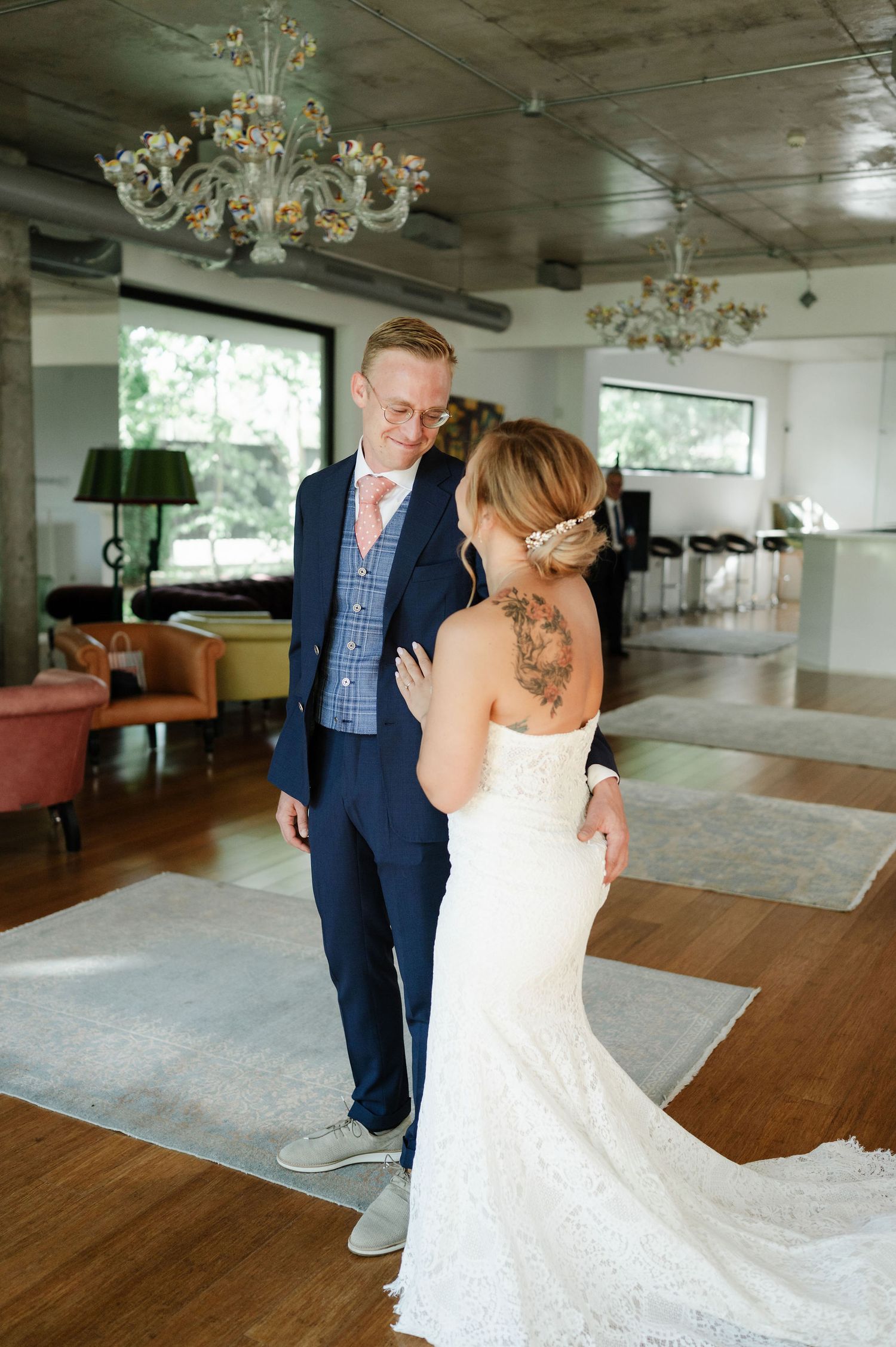 A romantic first look moment unfolds in an elegant room with a crystal chandelier.