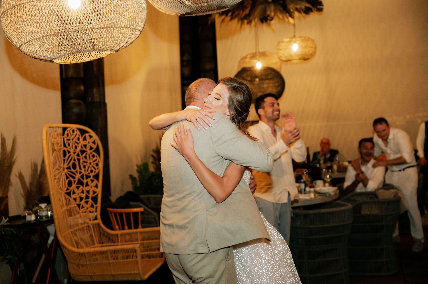 Couple sharing a romantic dance moment under warm lighting at an indoor wedding reception.