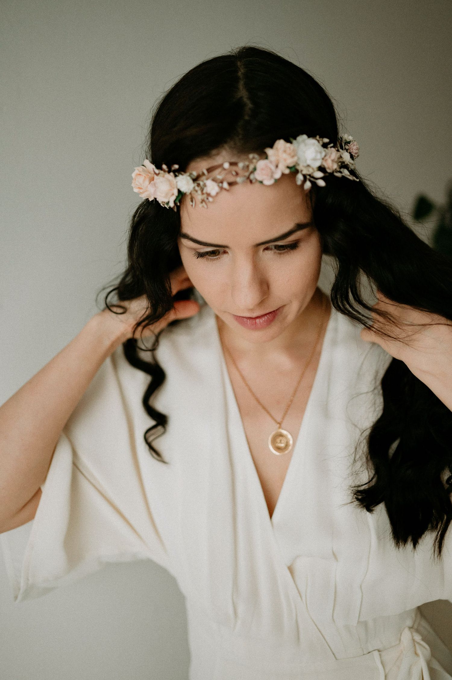 Romantic bridal boudoir photo with flowing white robe and floral headpiece.