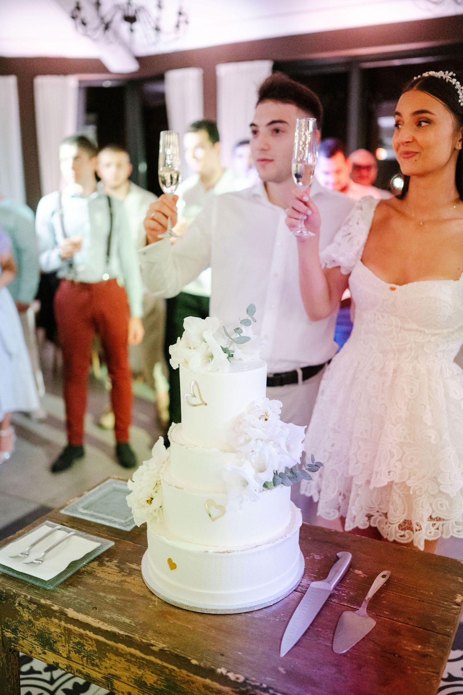 Traditional white wedding cake cutting ceremony at an indoor reception venue.
