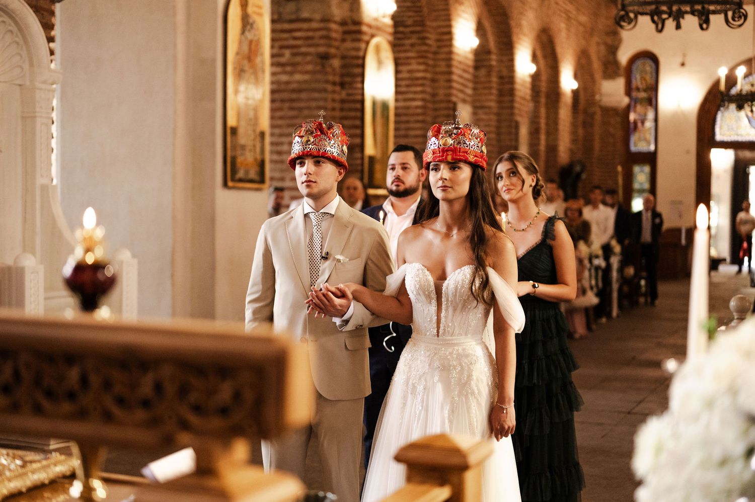 Wedding guests and clergy gathered in elegant church hallway with brick columns.