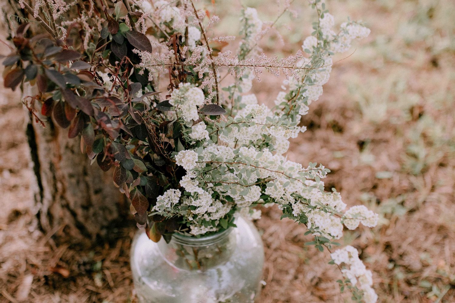 Delicate white floral arrangements in glass vases create an elegant rustic wedding decor display.