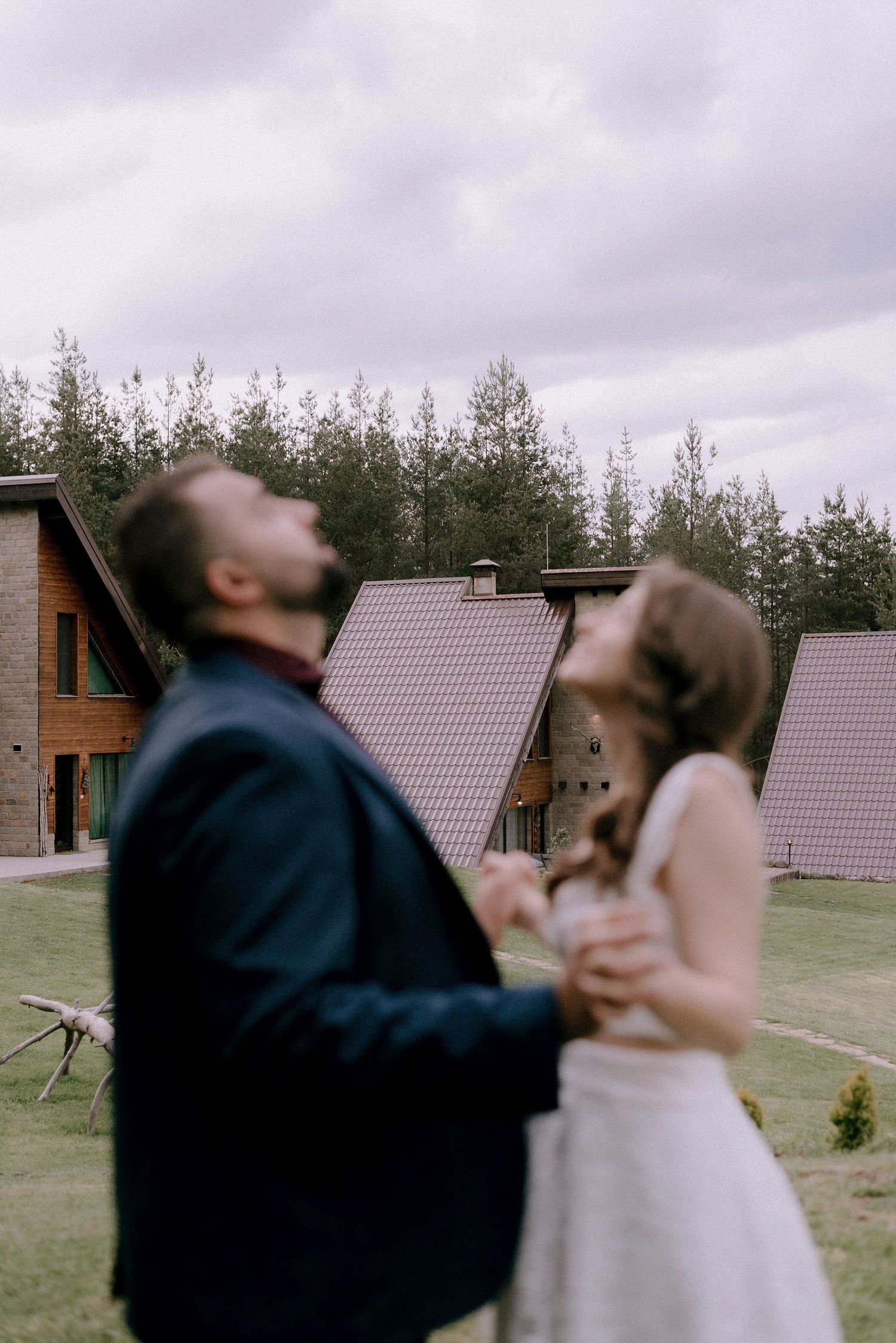 A couple dances outside rustic cabins during their wedding celebration.