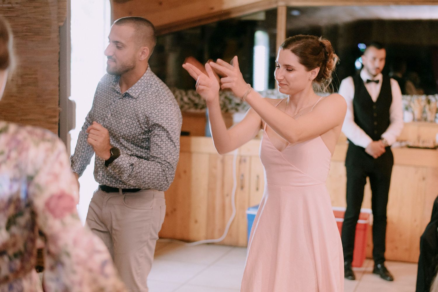 Wedding reception guests dancing and celebrating in a rustic venue with string lights overhead.