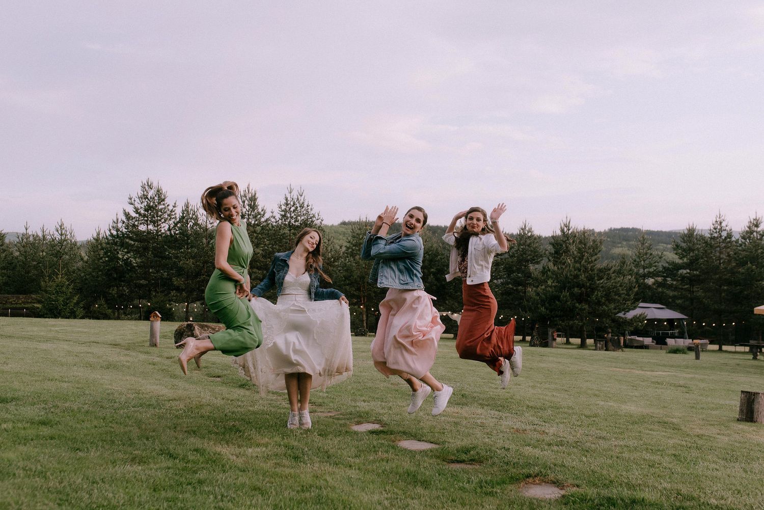 People jumping and playing together on a grassy field at dusk.