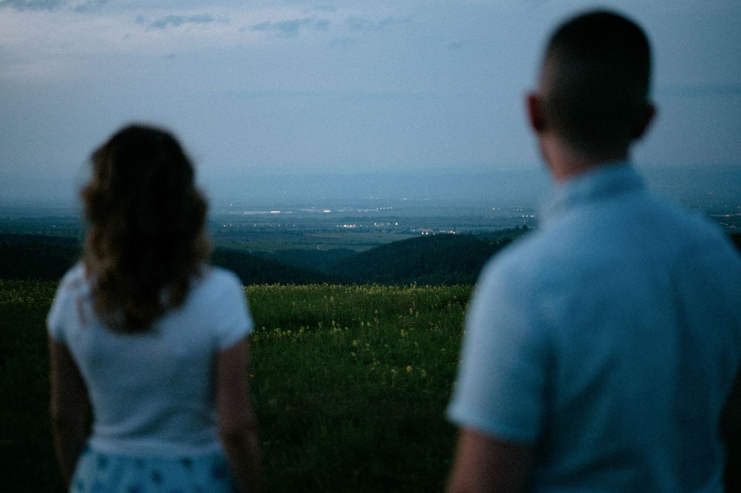 Two figures silhouetted against a dusky sky gaze at the distant horizon.