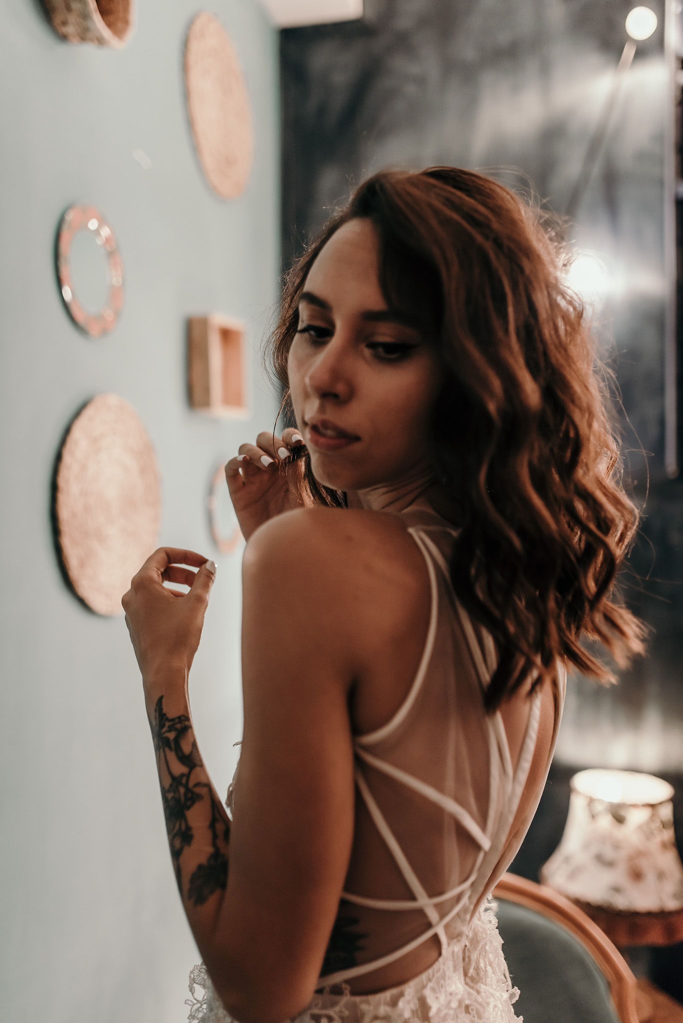 Artistic boudoir photography showing strappy dress details and tattoo against a teal wall.