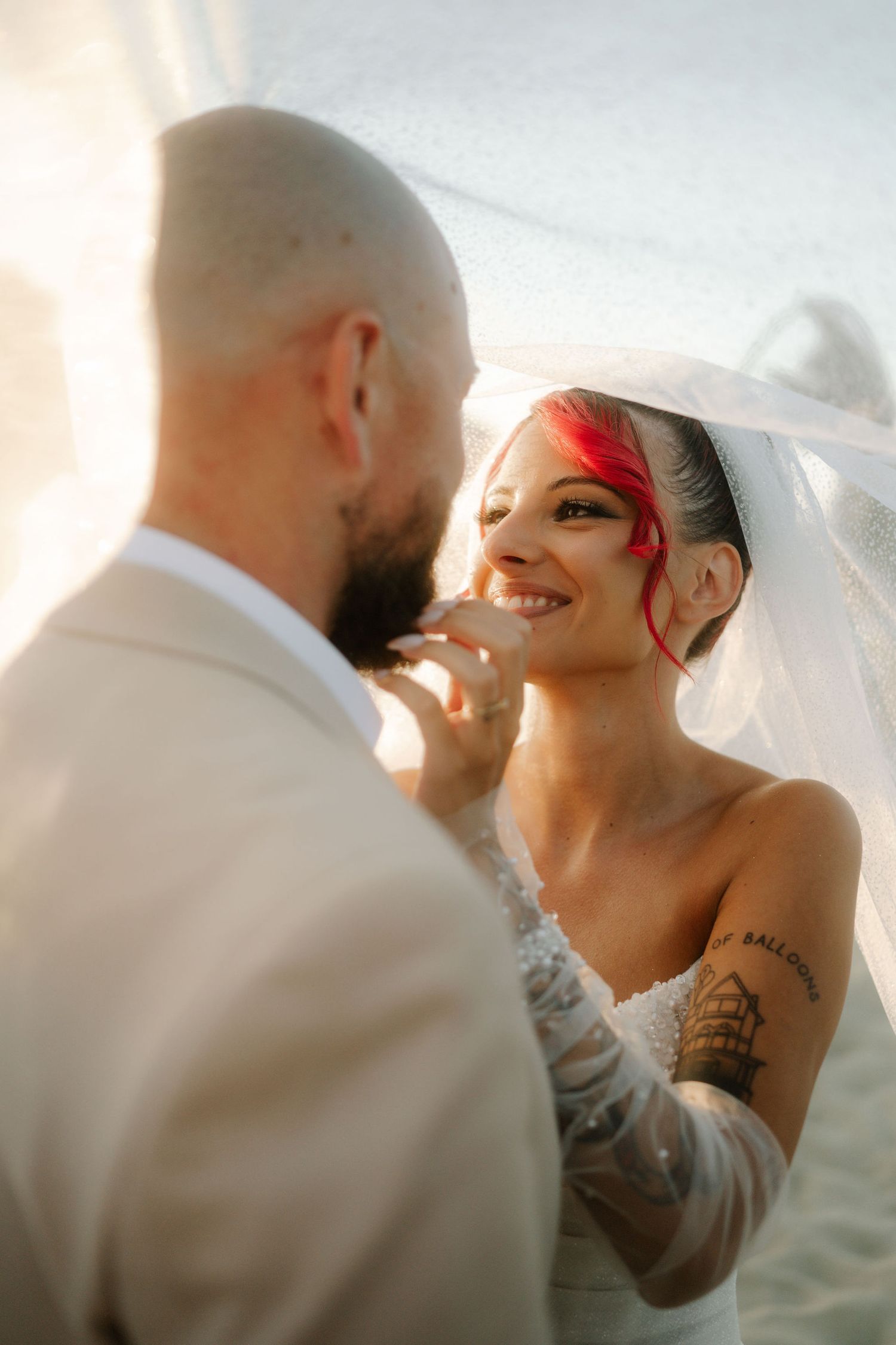 A romantic wedding couple embraces in soft sunlight creating a dreamy silhouette against a bright sky.