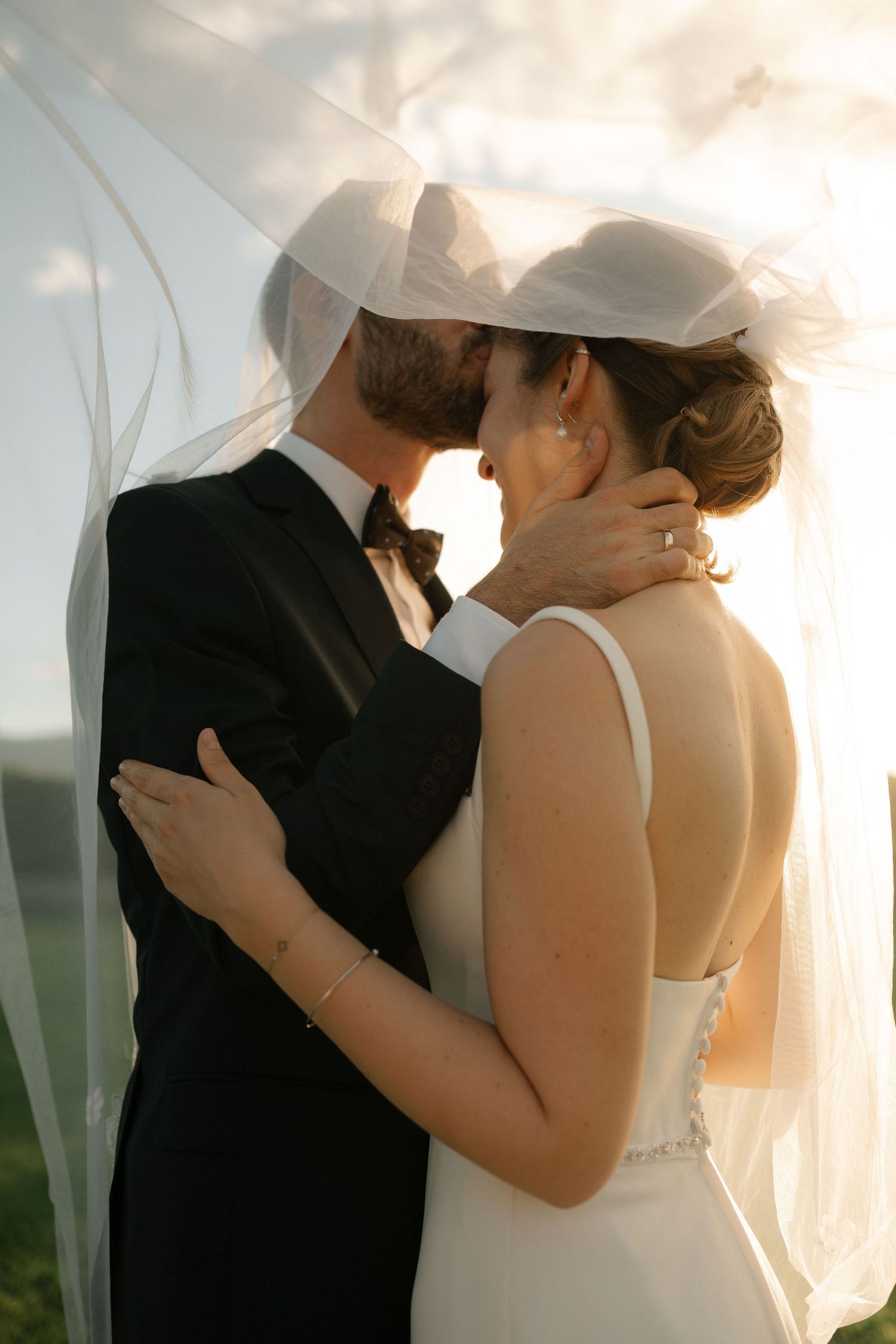 Romantic wedding couple embraces under a flowing veil during sunset, shown in multiple artistic close-up shots.