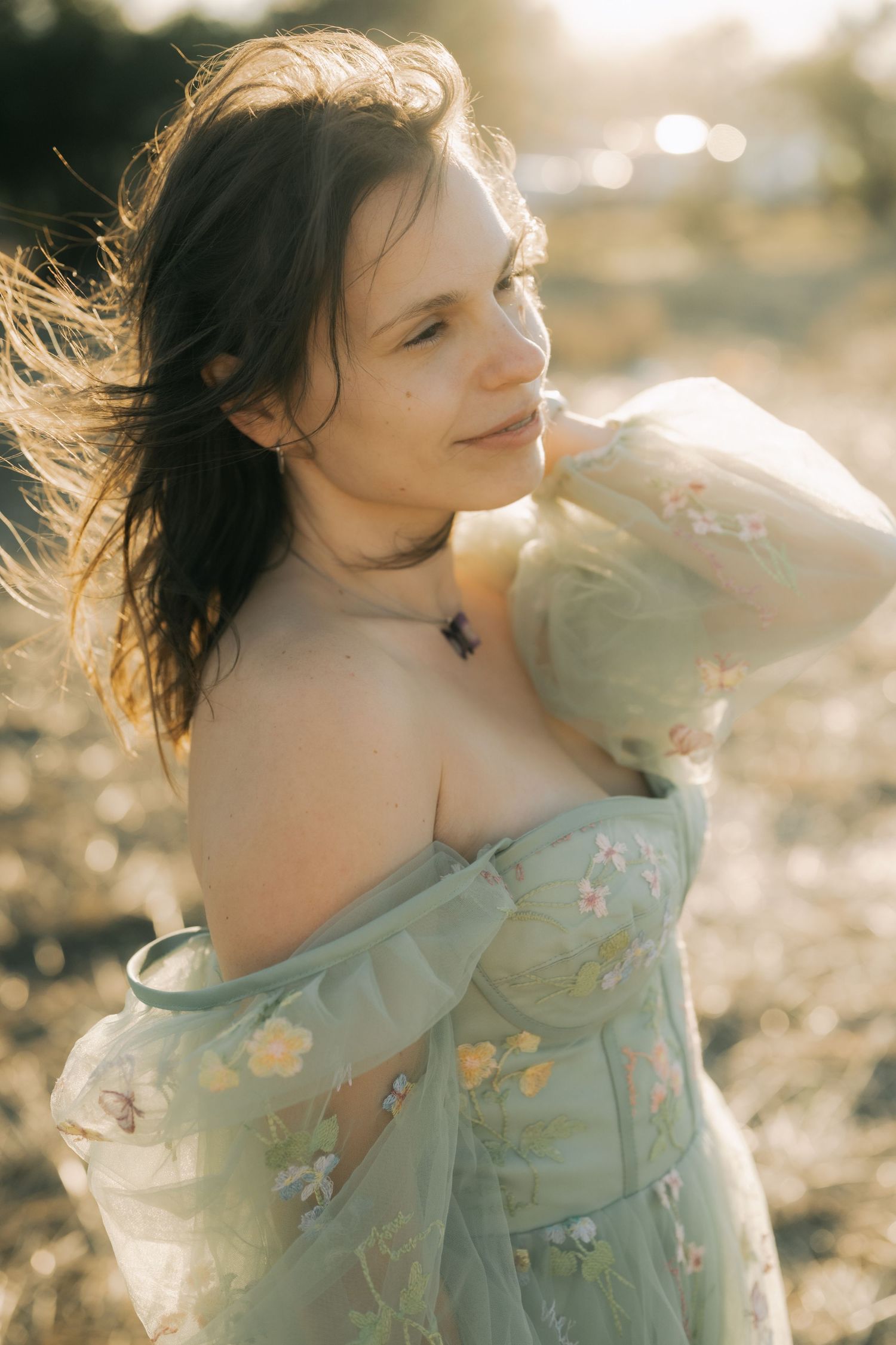 A dreamy portrait series of someone in a flowing floral dress with sunlit bokeh effects in the background.