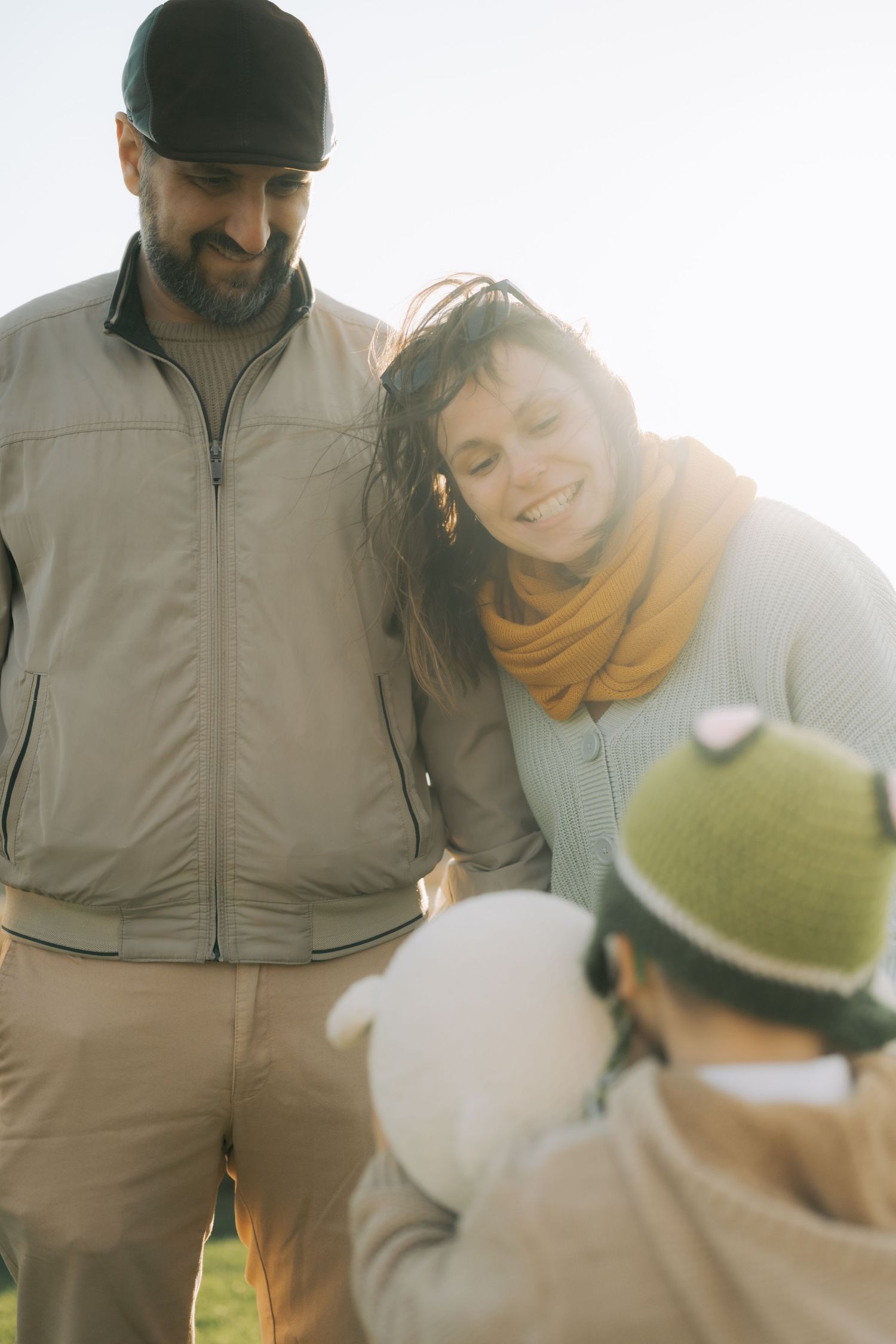 A series of warm sunlit photos showing tender moments between parent and child in casual outdoor wear.