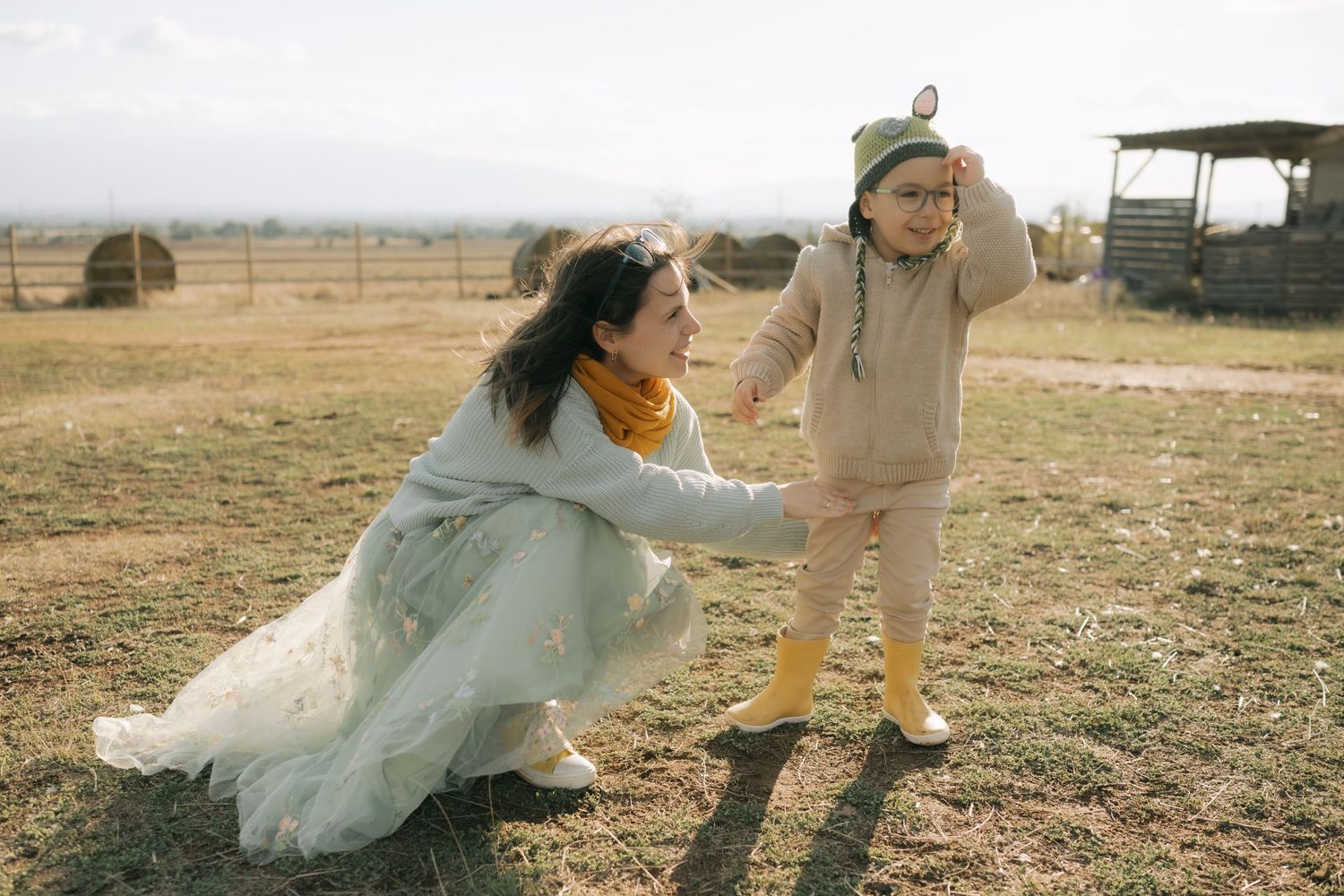 A couple in wedding attire playfully runs through a field during golden hour.