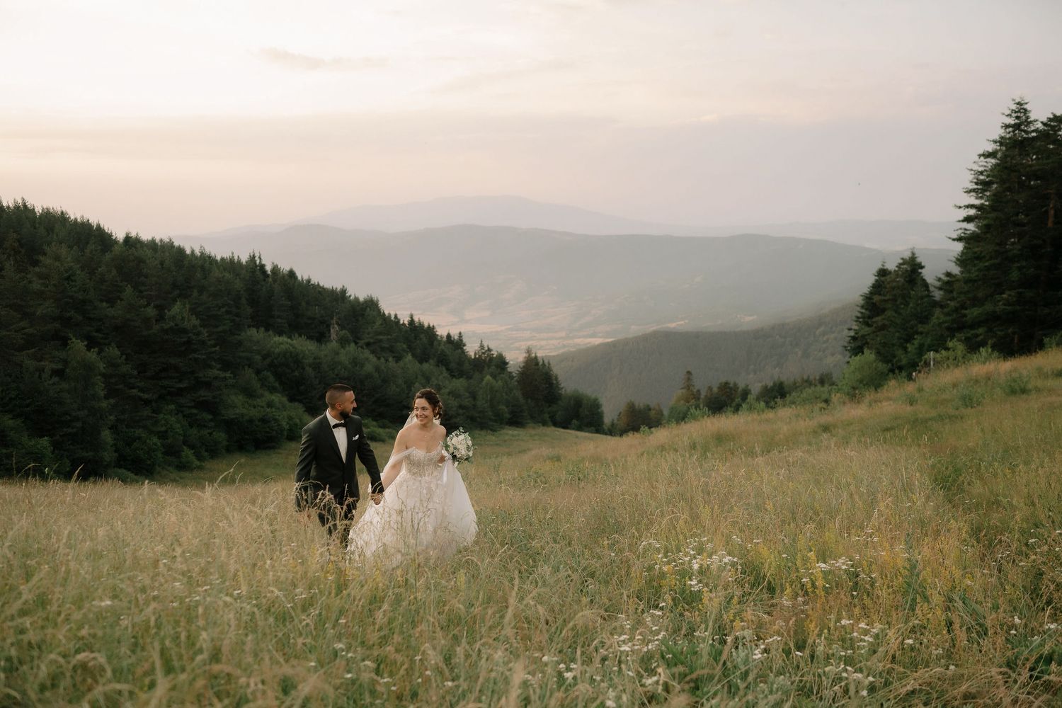 A couple walks through a scenic mountain meadow during sunset in the Pacific Northwest.