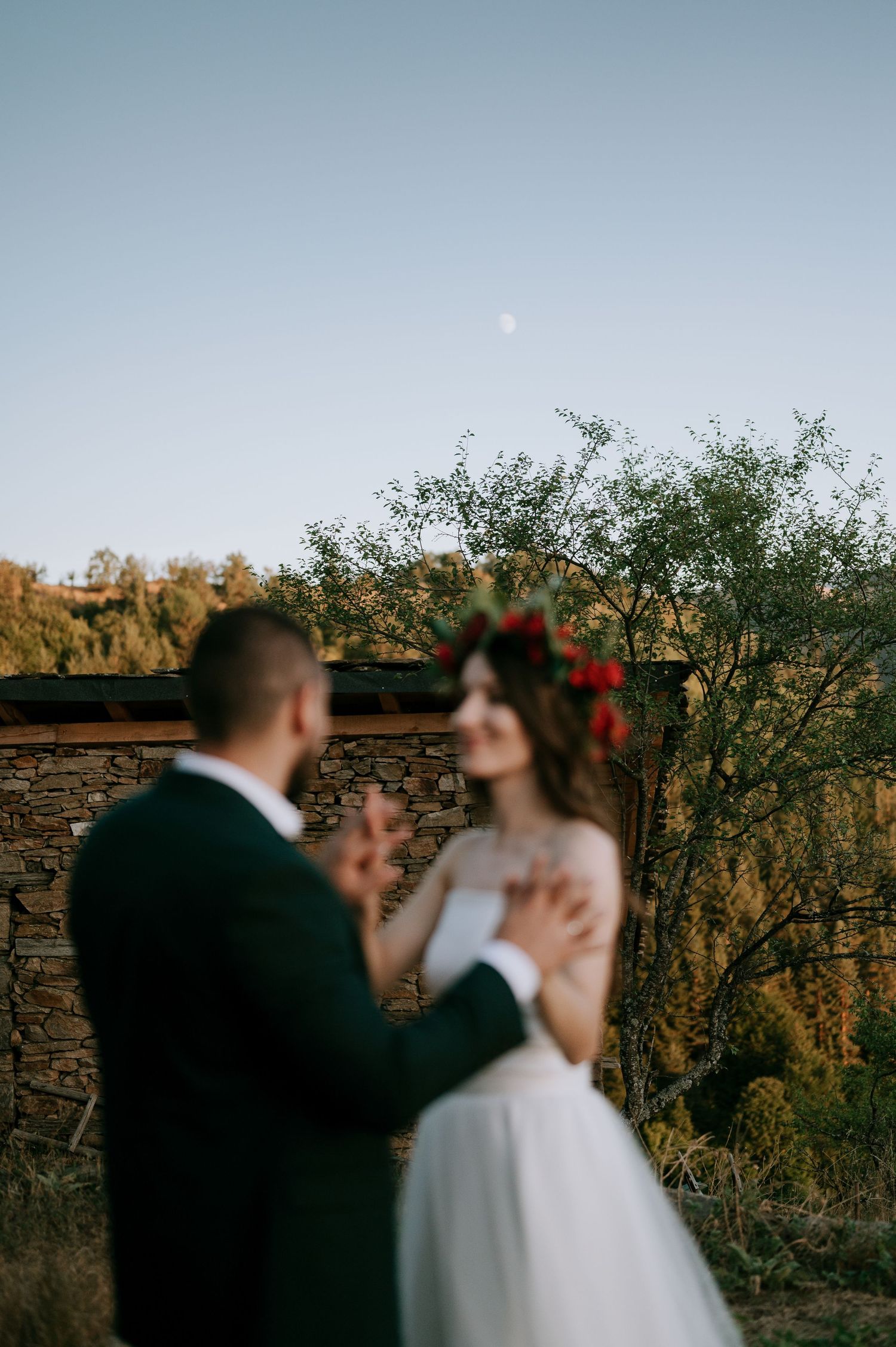 Dreamy wedding portraits at dusk with stone wall and natural landscape in background.