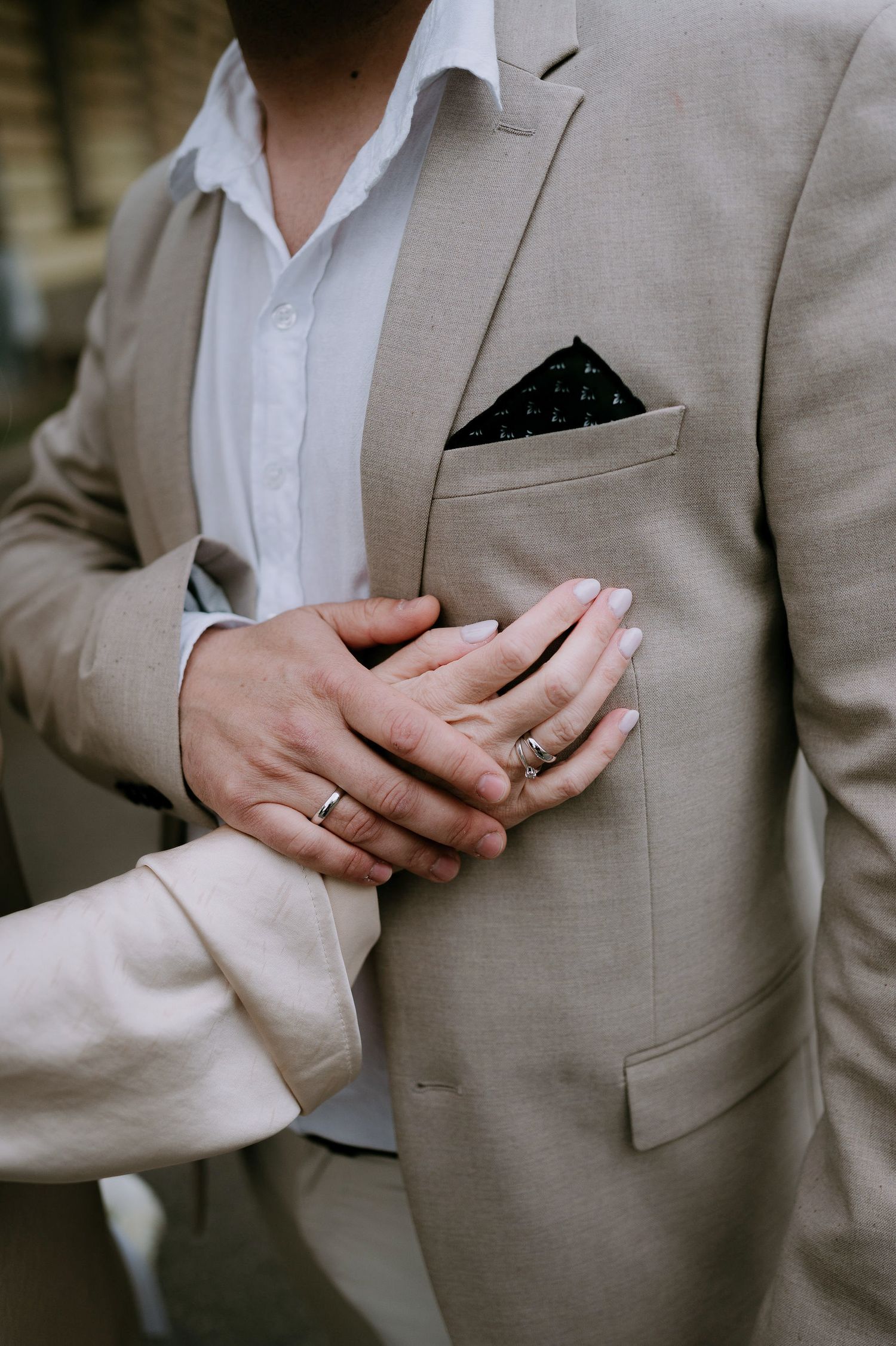 Close-up details of formal attire showing rings and suit pocket square.