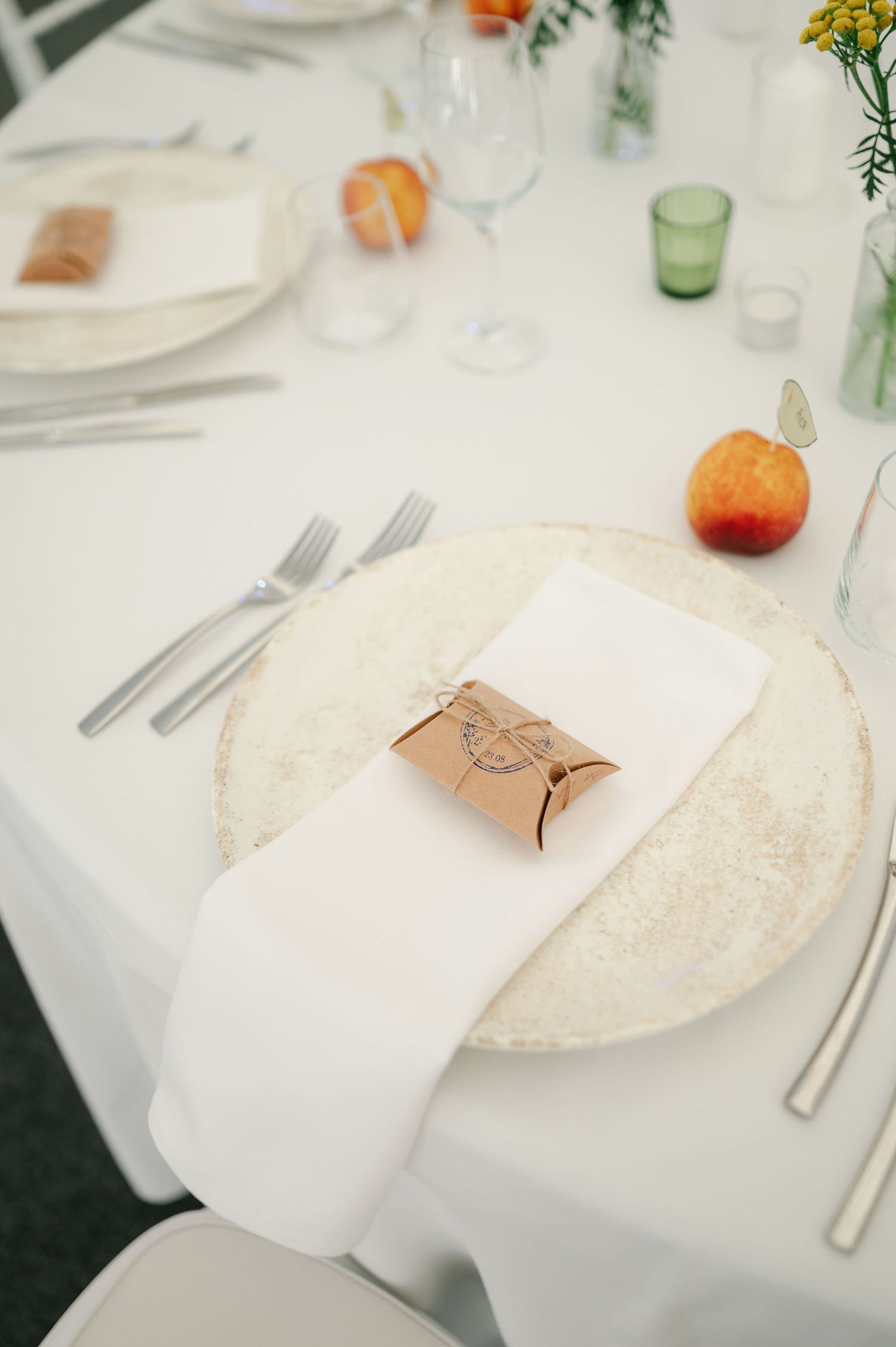 Elegant table setting with white linens, clear glassware, and orange accents at a wedding reception.