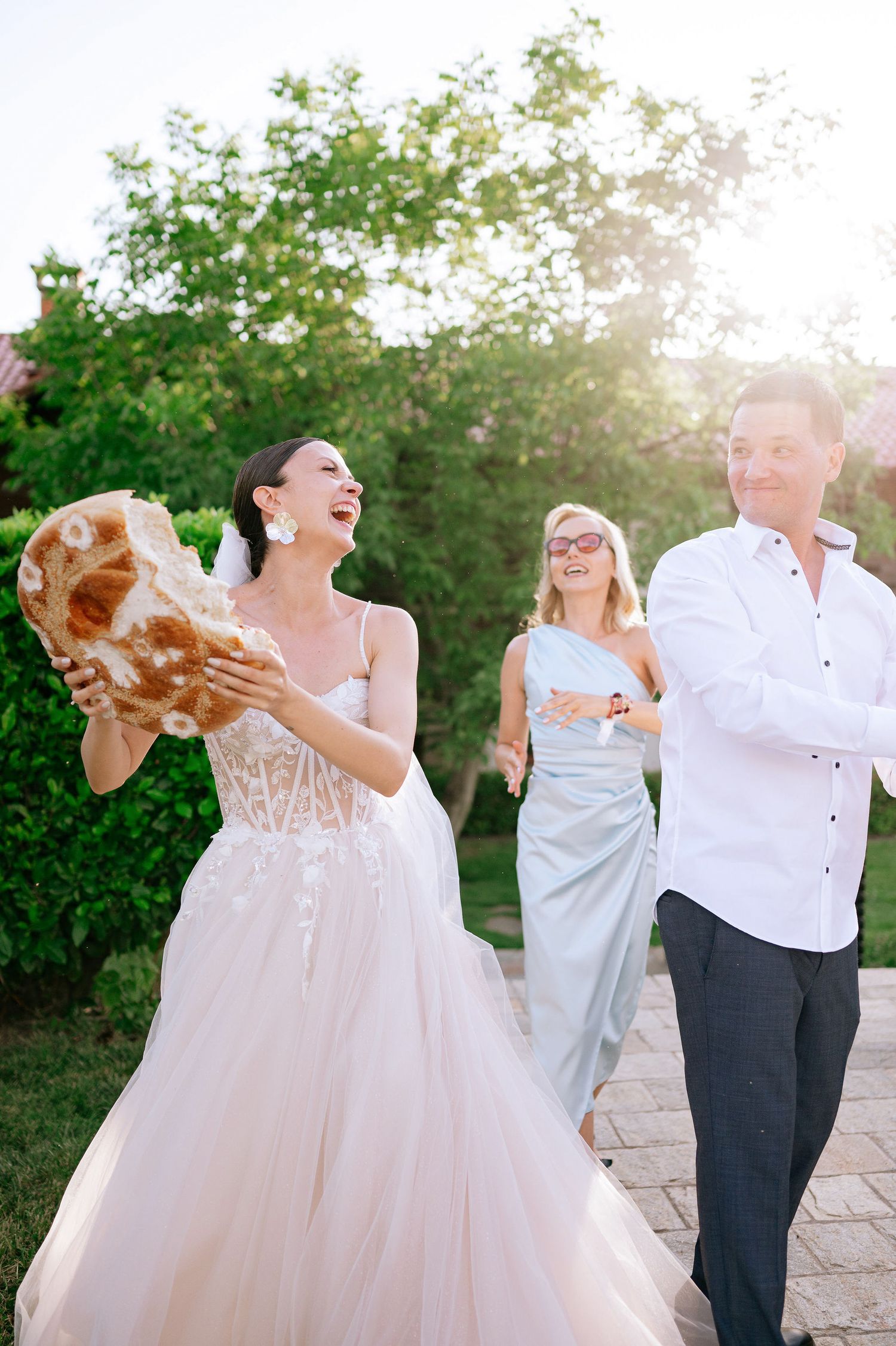 Wedding couple dances together on a stone patio with greenery in the background.