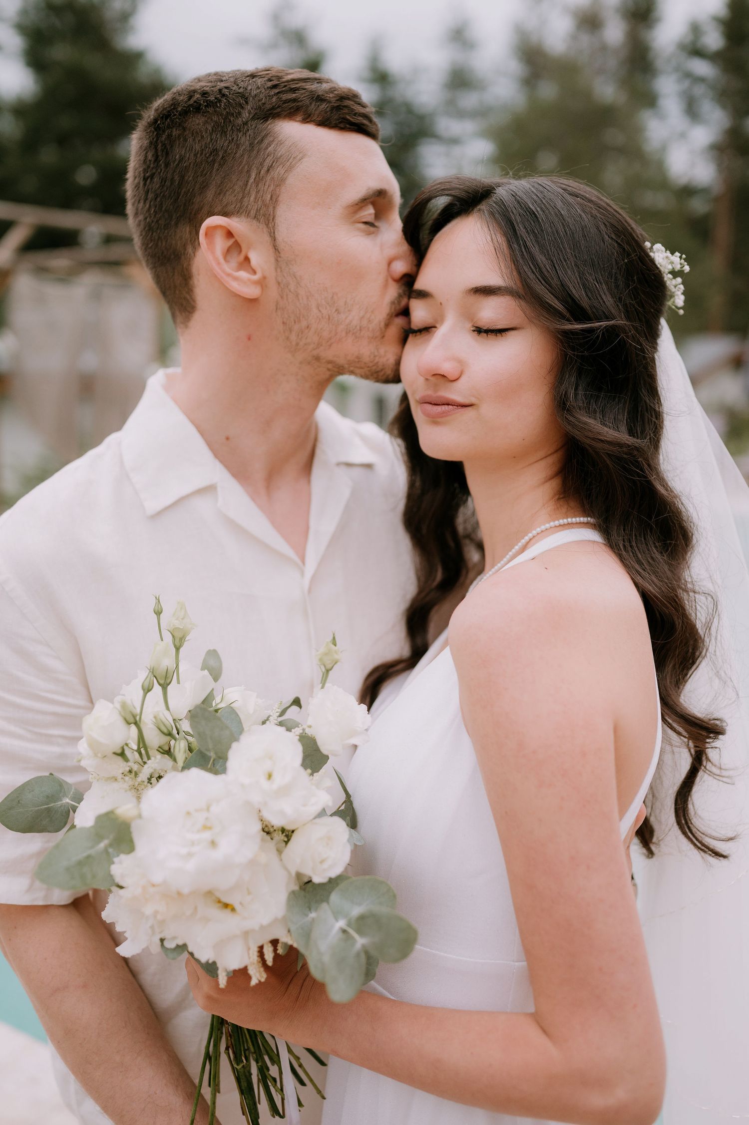 Romantic wedding portraits with white floral bouquet against a serene pool backdrop.