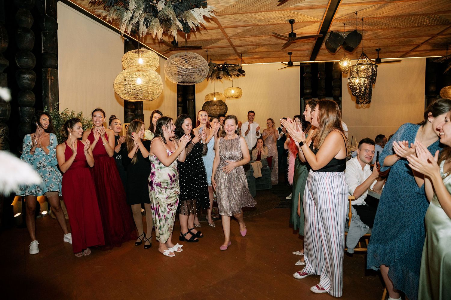Wedding guests dancing and having fun in an indoor venue with wooden beams.