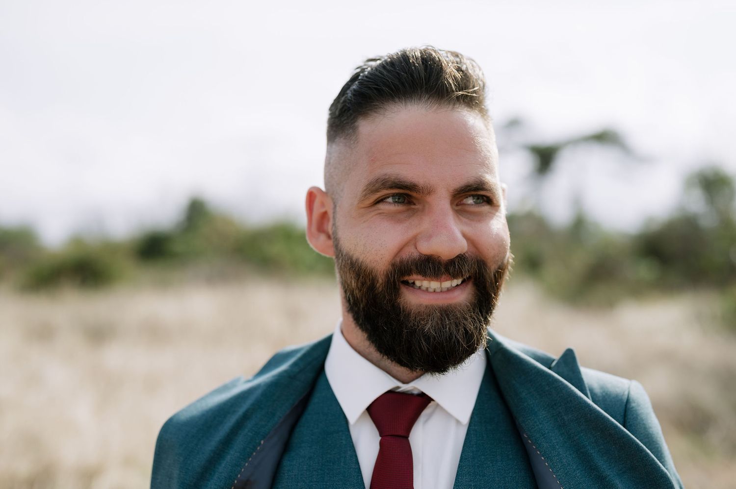 Close-up profile view of someone wearing a dark suit and burgundy tie.