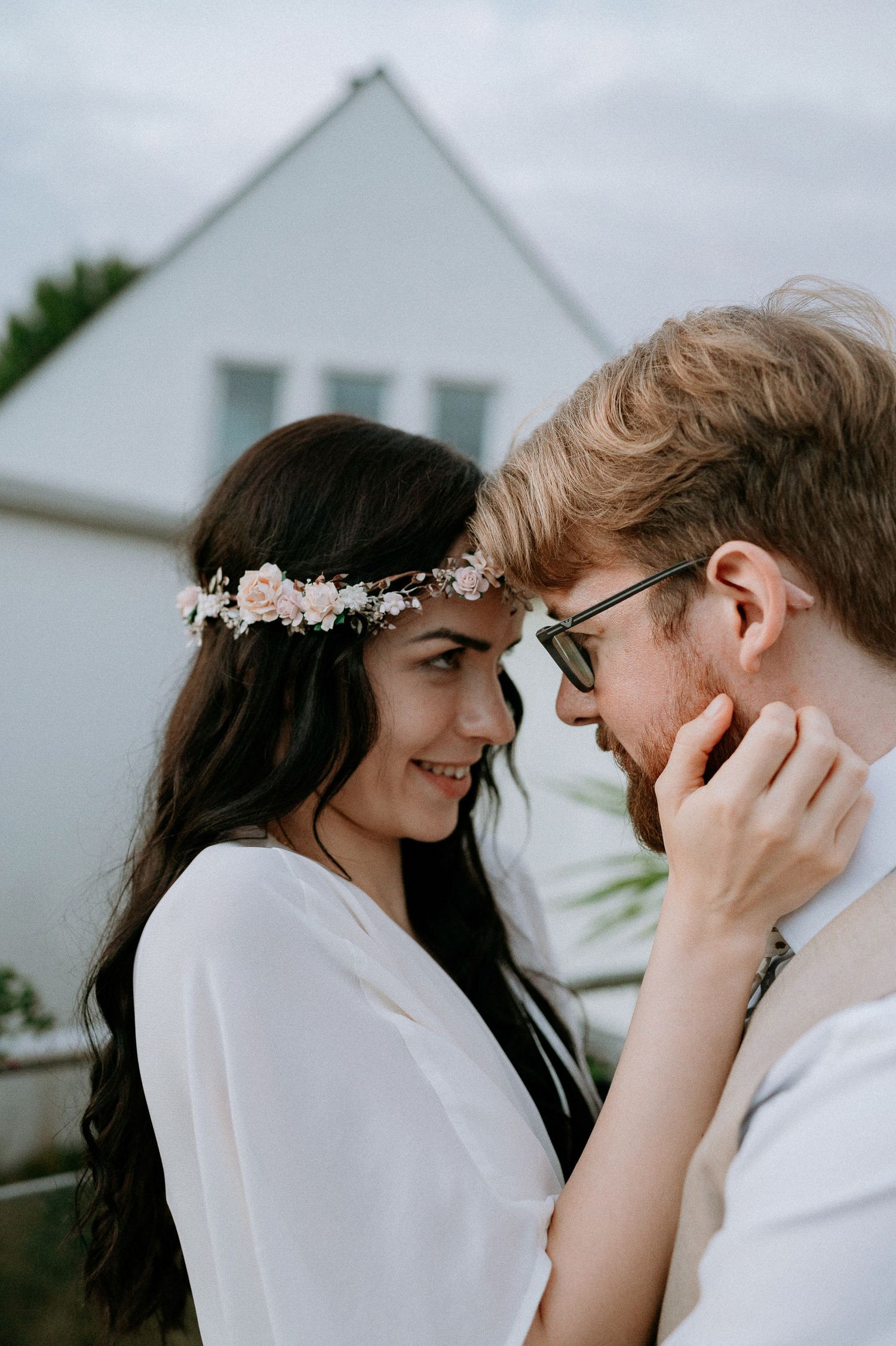 An intimate moment between newlyweds in front of a white house.