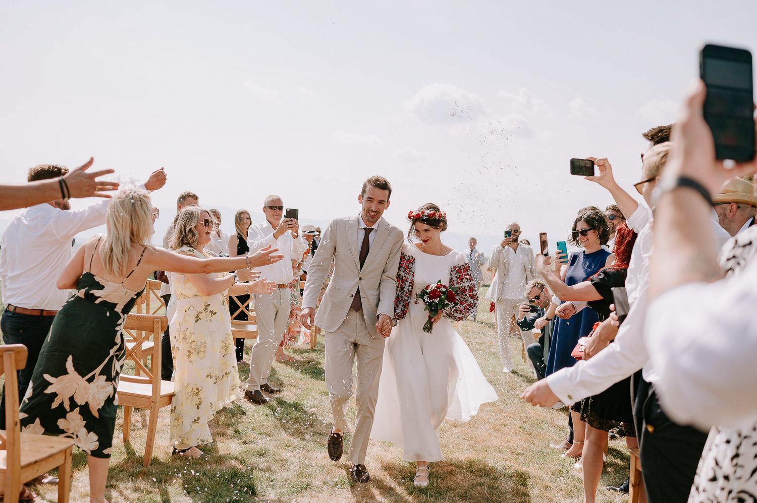 Celebratory moment at an outdoor wedding with guests cheering and taking photos.