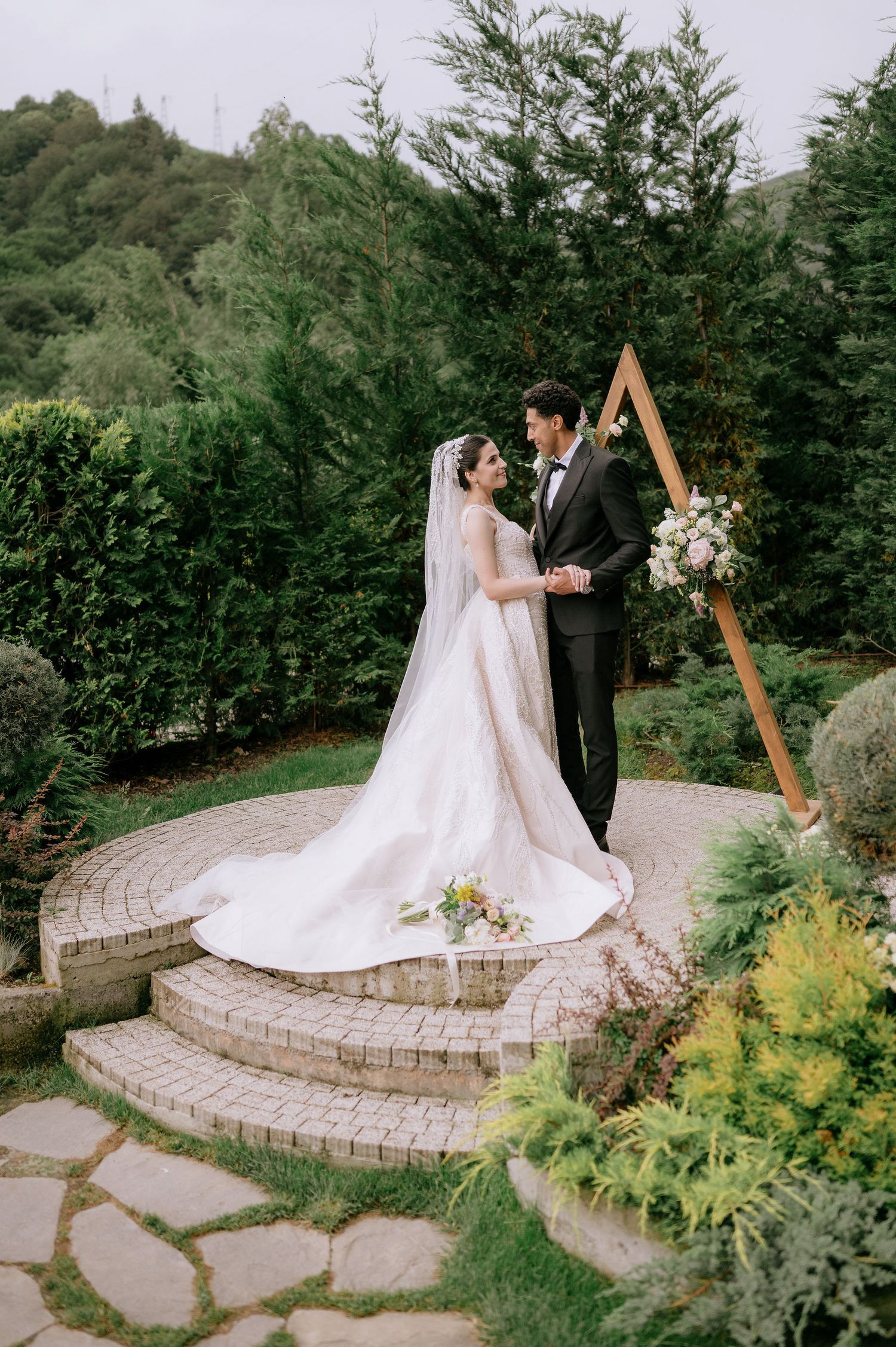Scenic wedding portrait setting with stone platform, wooden arch and mountain landscape views.