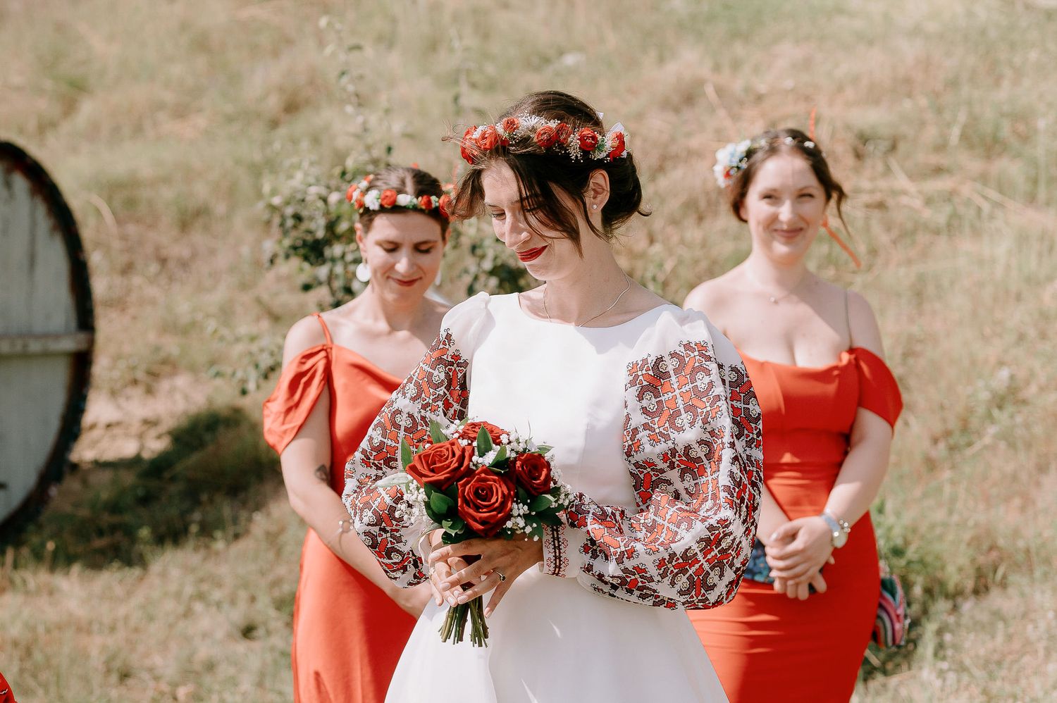 Outdoor wedding scene with bridal party in coral and white attire.