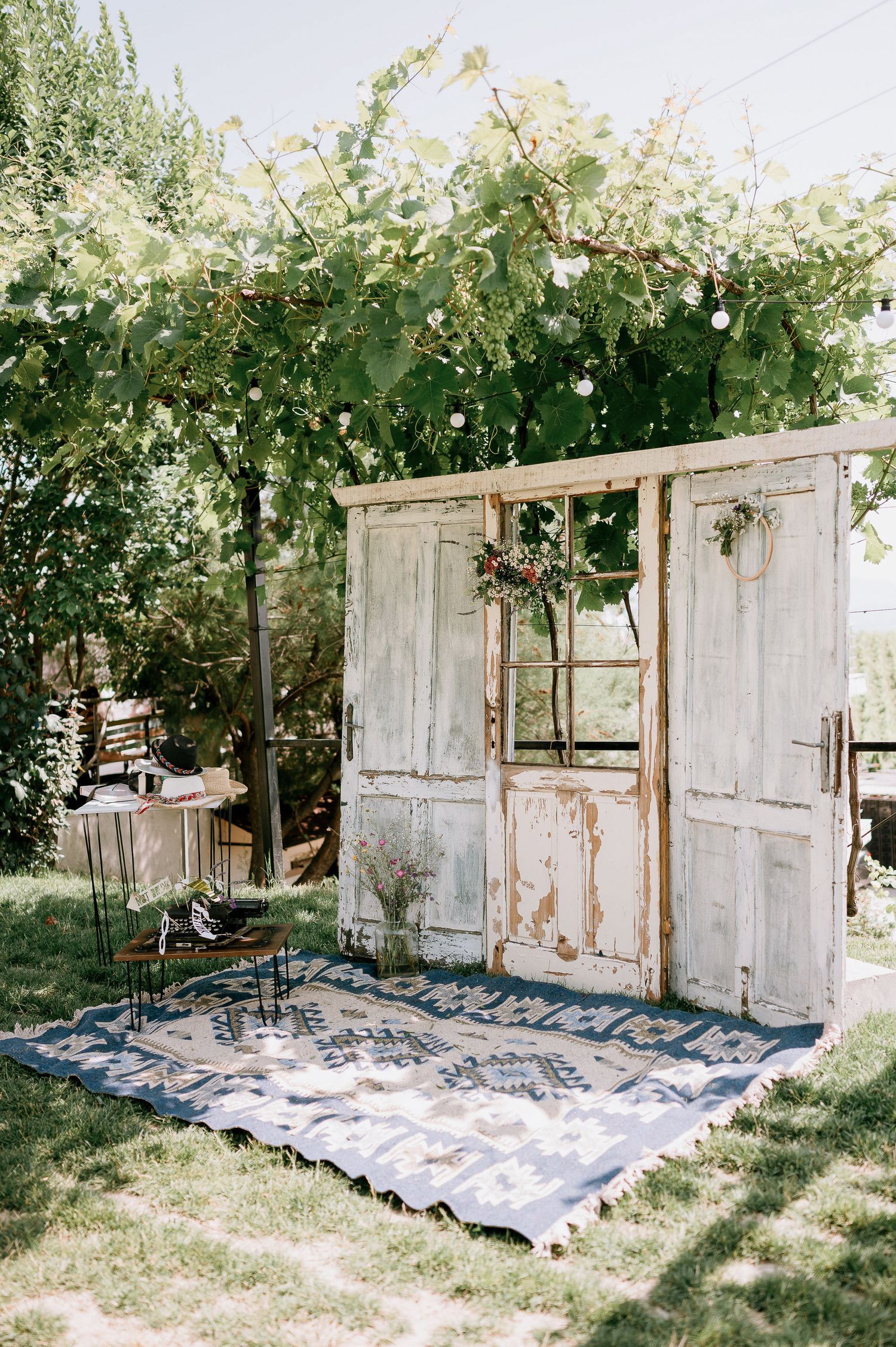 Rustic vintage doors arranged outdoors with blankets creating a unique wedding backdrop.