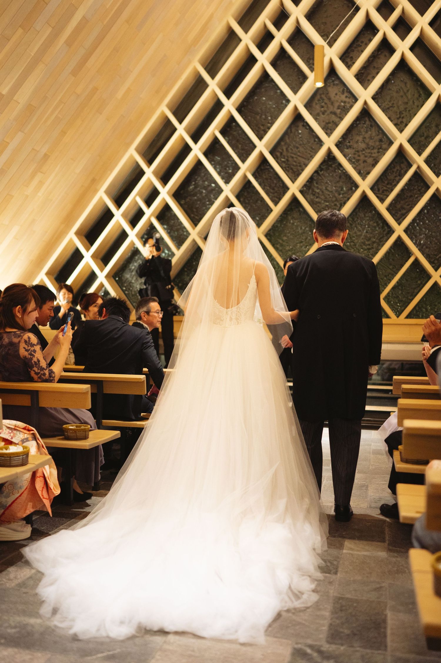 Wedding ceremony in modern chapel with geometric lattice wall design.