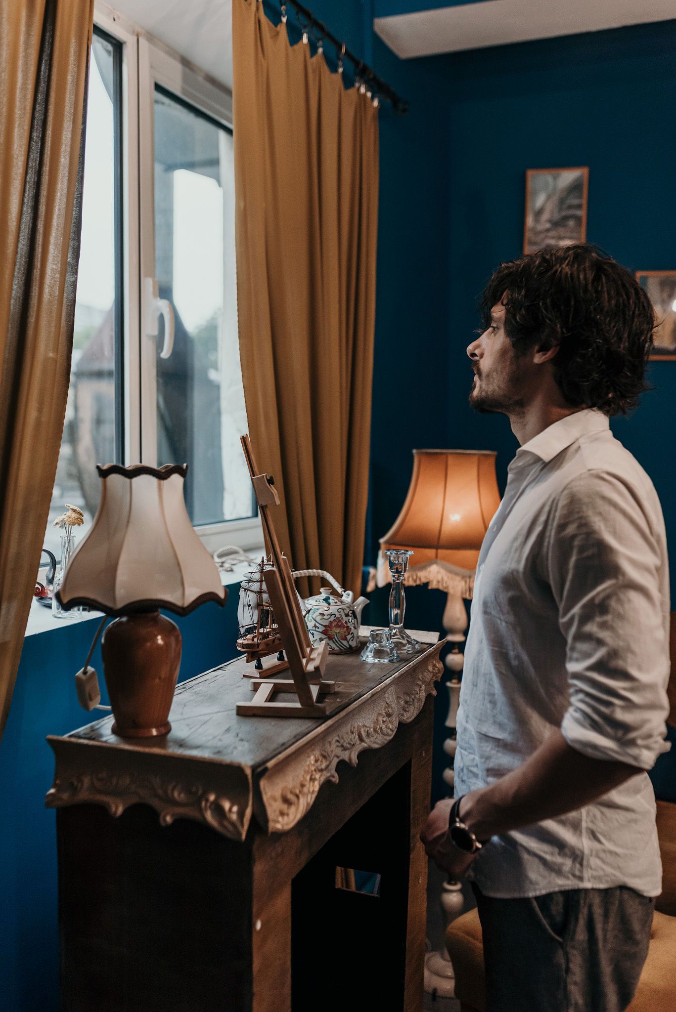 Interior scene with table lamp and curtains against deep blue walls.