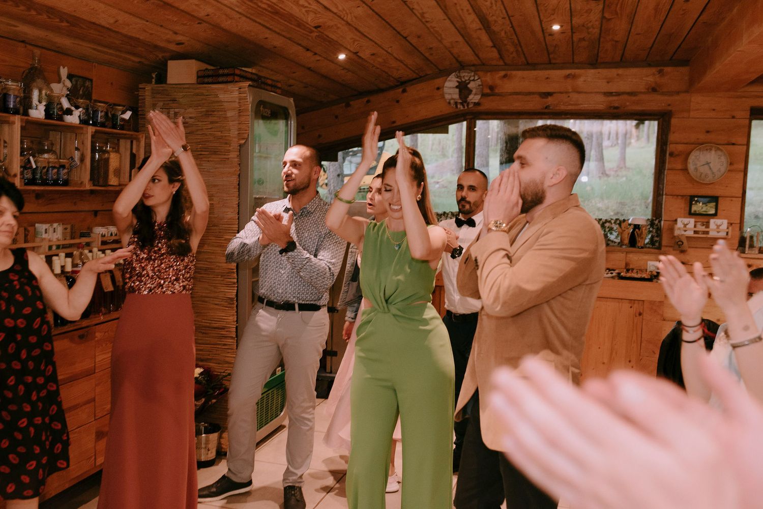 People dancing and celebrating inside a wood-paneled room with string lights.