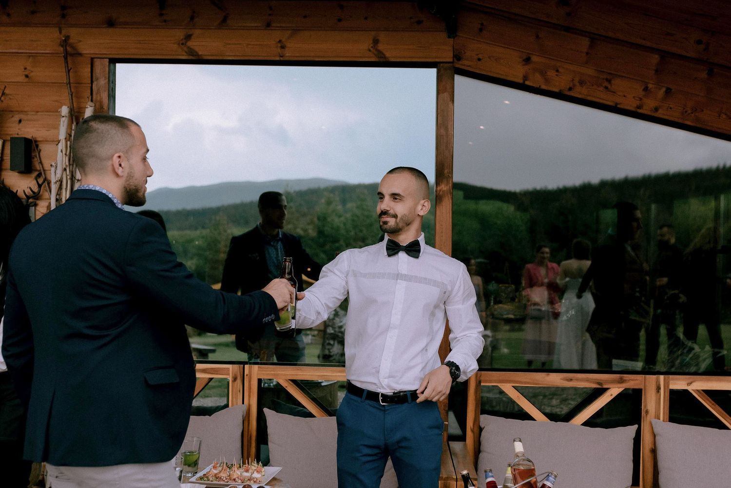 Wedding reception under wooden pavilion with mountain views in background.