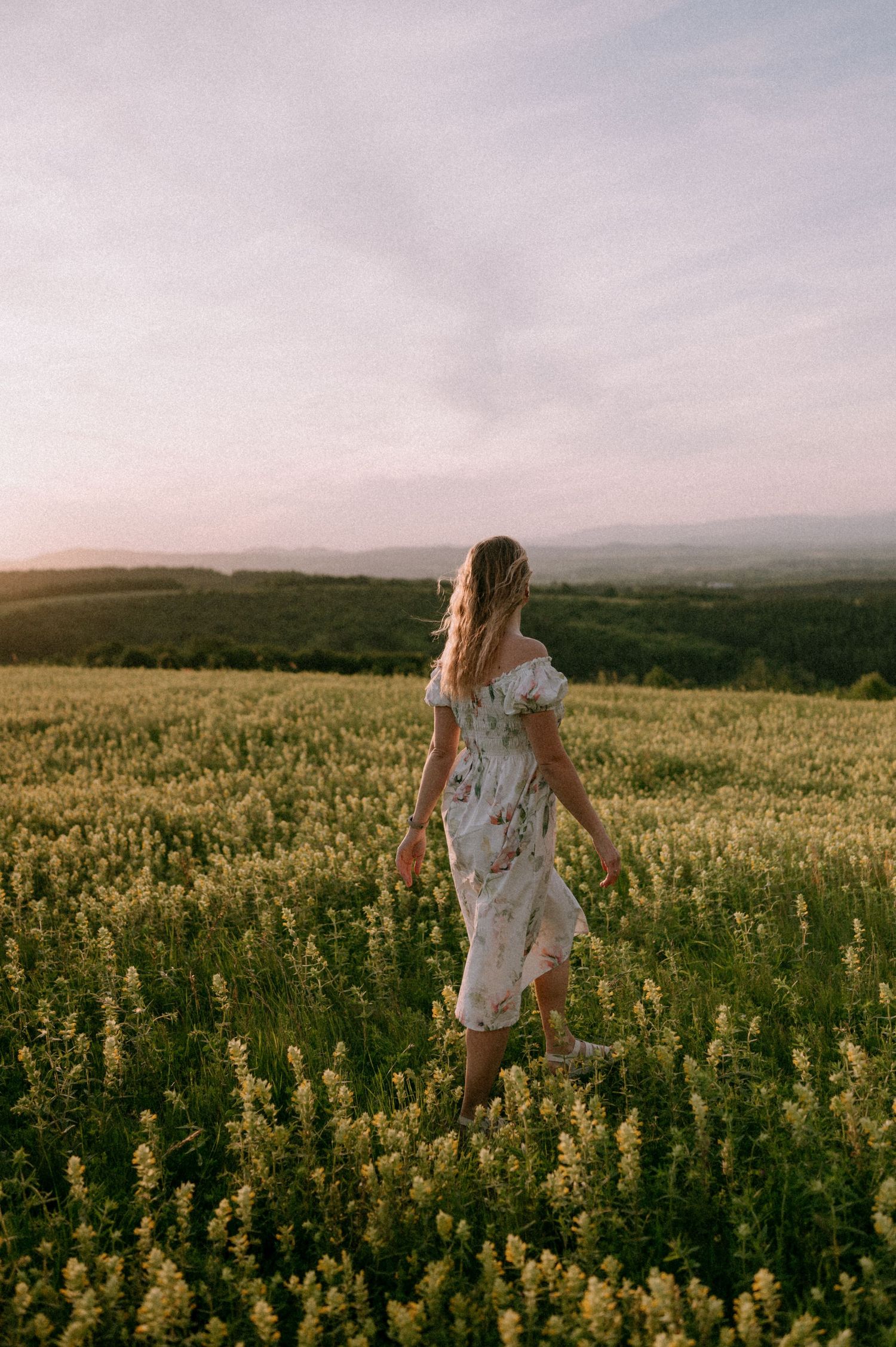 Figure dancing through a vast yellow canola field under cloudy skies.