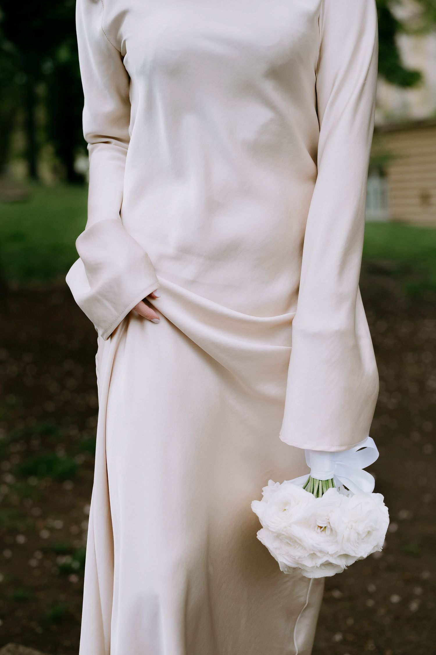 Detail shot of white formal attire with delicate flower accents in an outdoor setting.